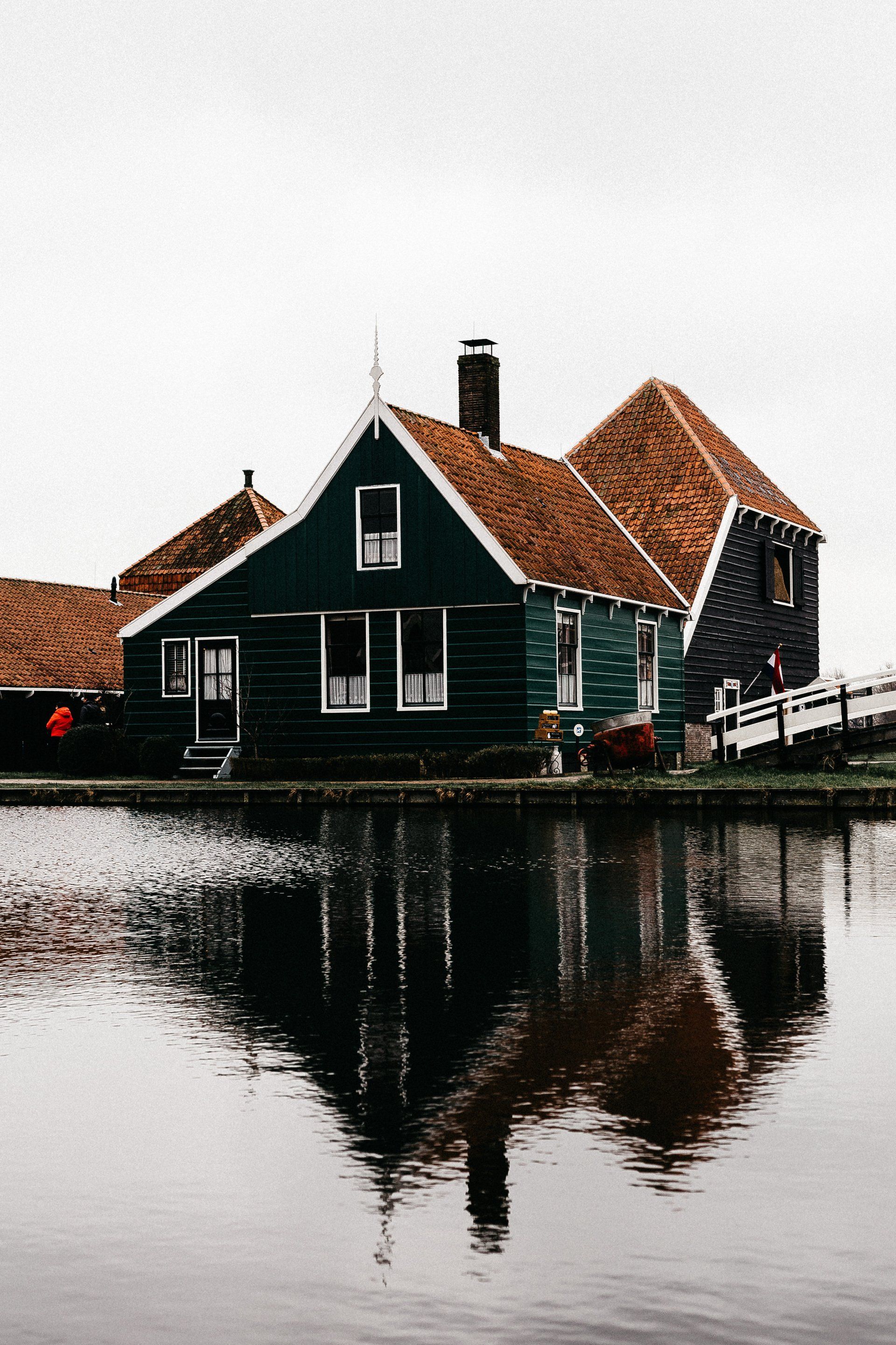 a green house sits next to a body of water
