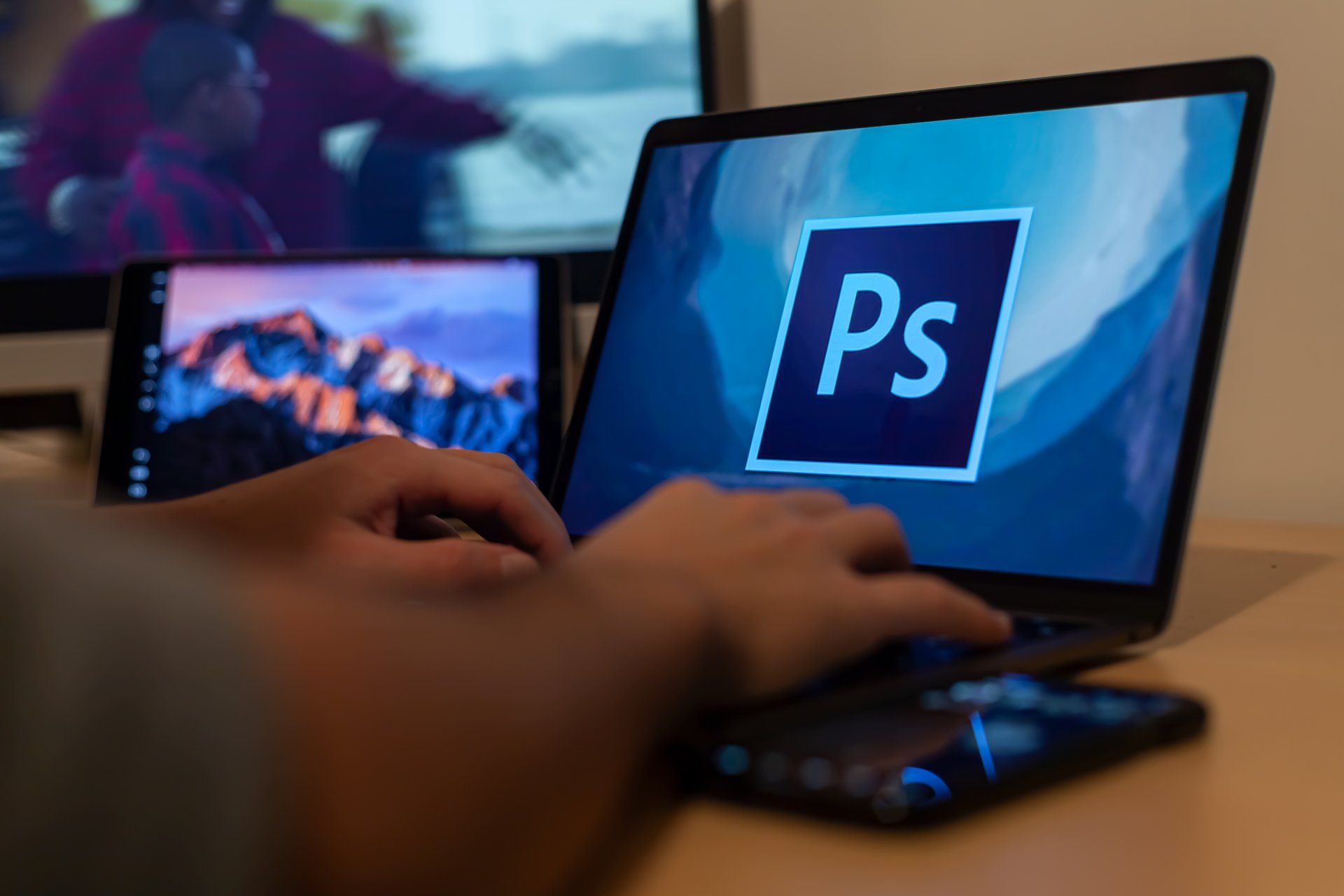 A person is typing on a laptop with a ps logo on the screen.