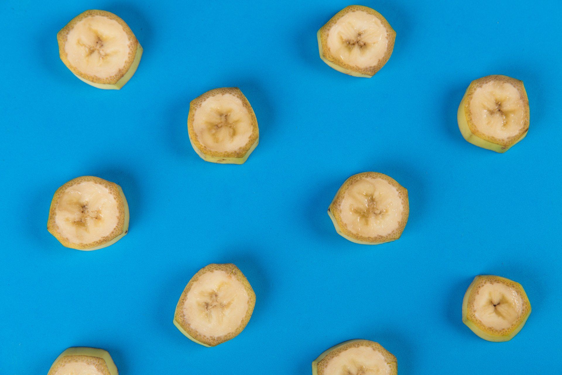 Banana slices scattered on a blue background.