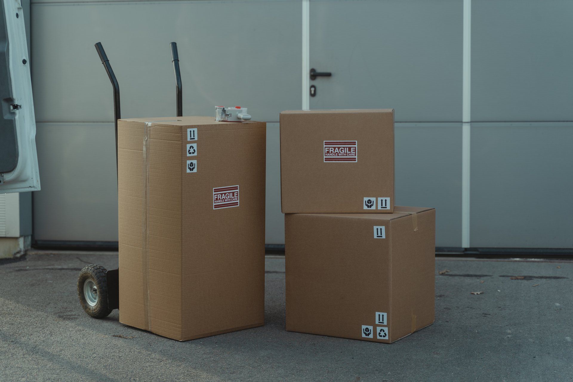 Three cardboard boxes are stacked on top of each other in front of a garage door.