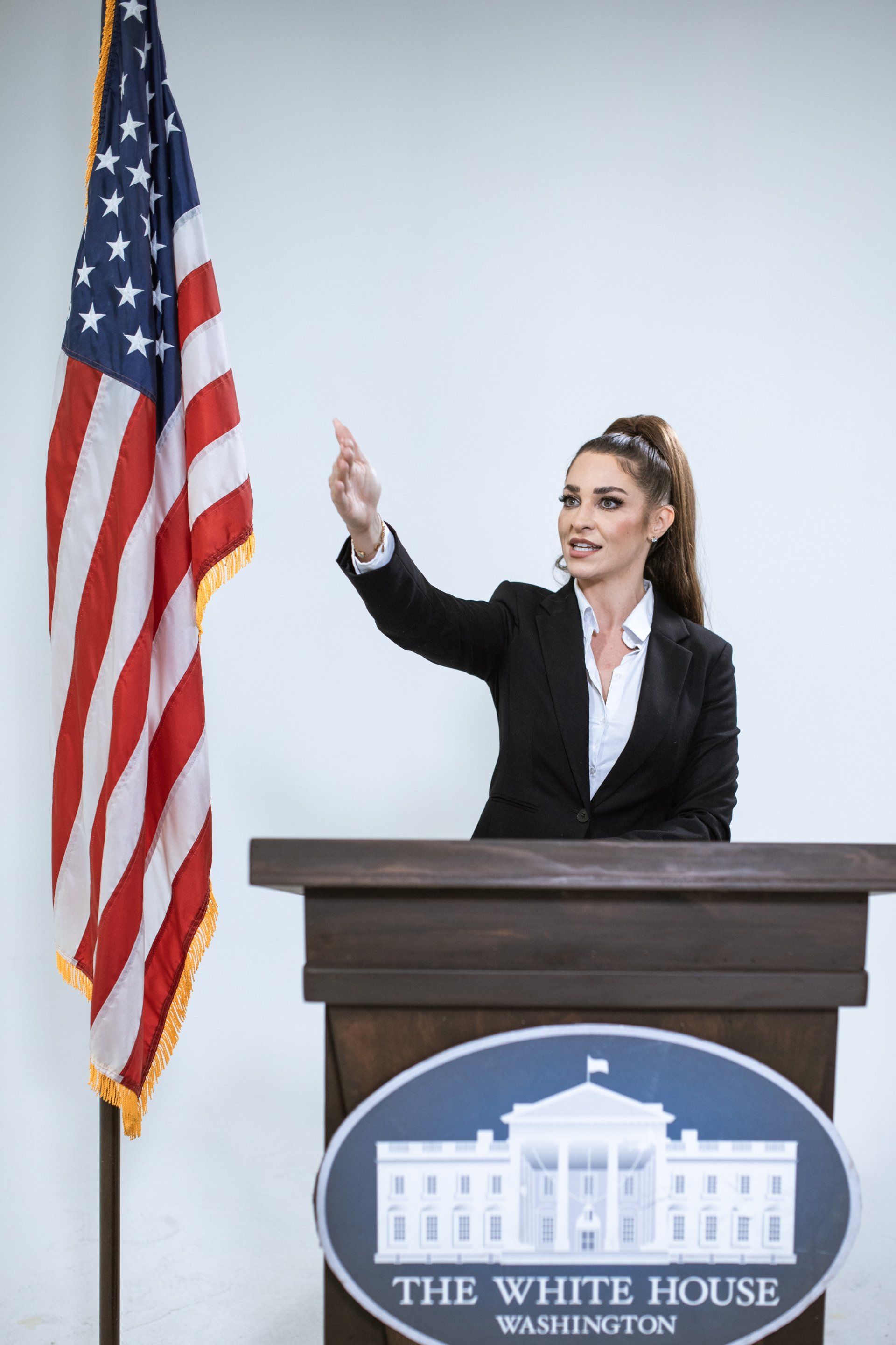 A woman is standing at a podium in front of an american flag.