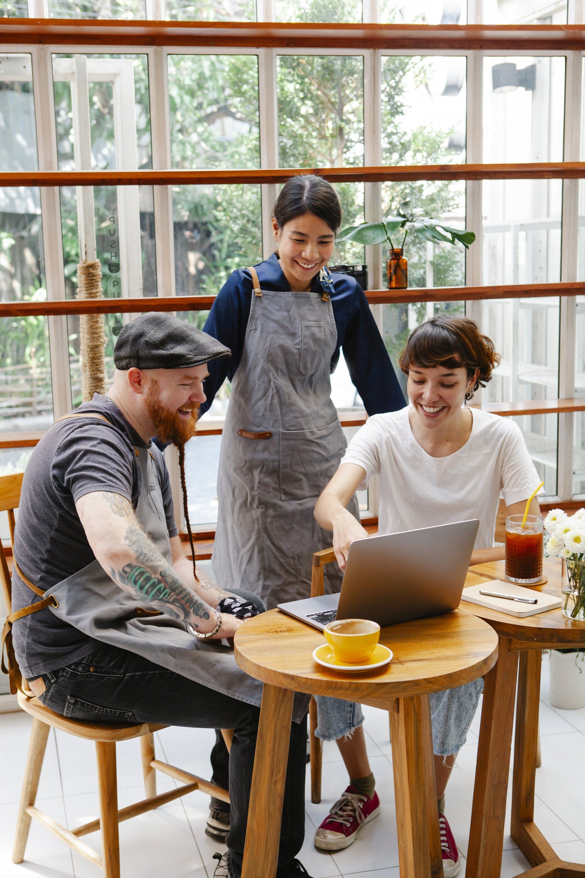 A group of people are sitting at a table looking at a laptop.