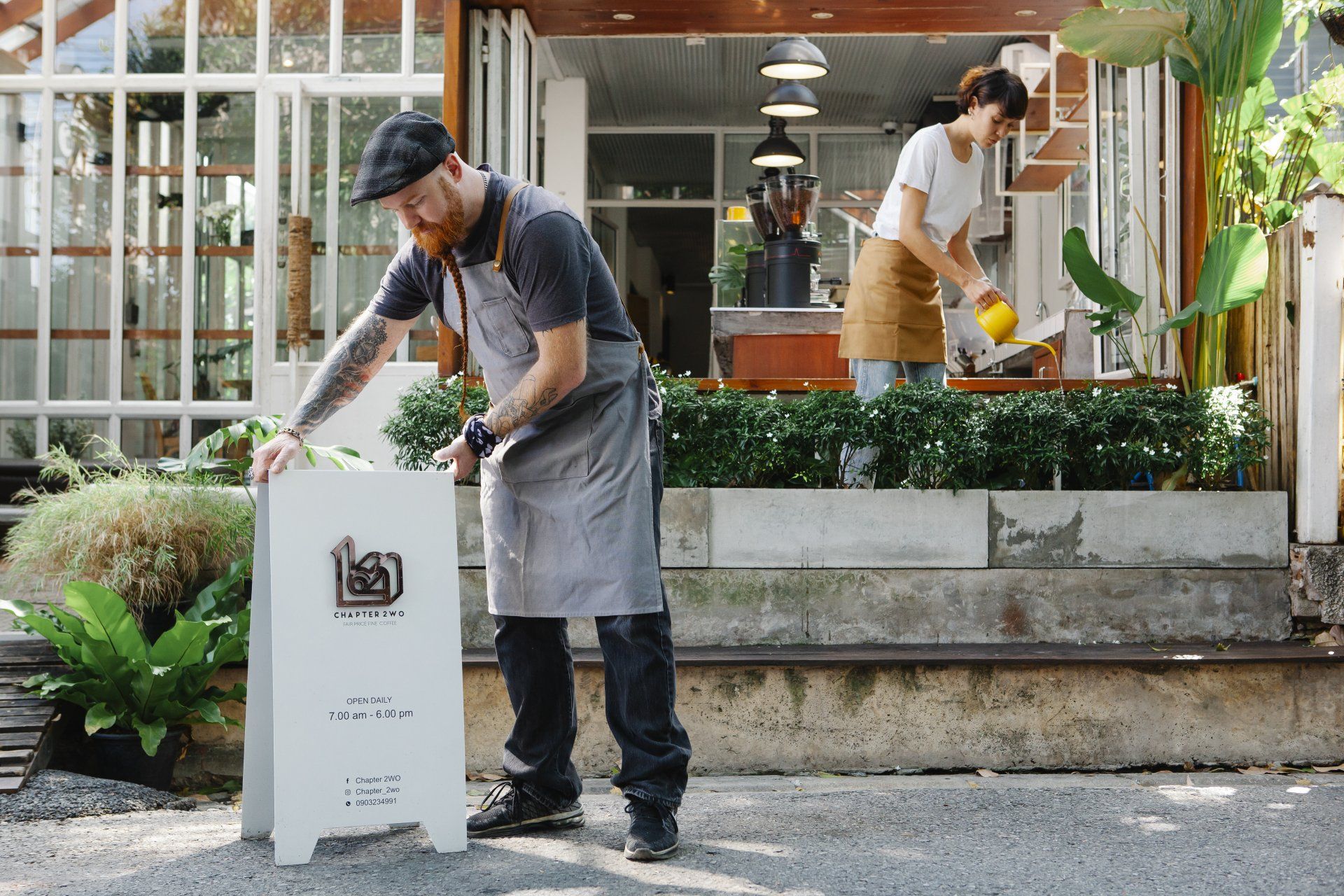 A man and a woman are working outside of a restaurant.