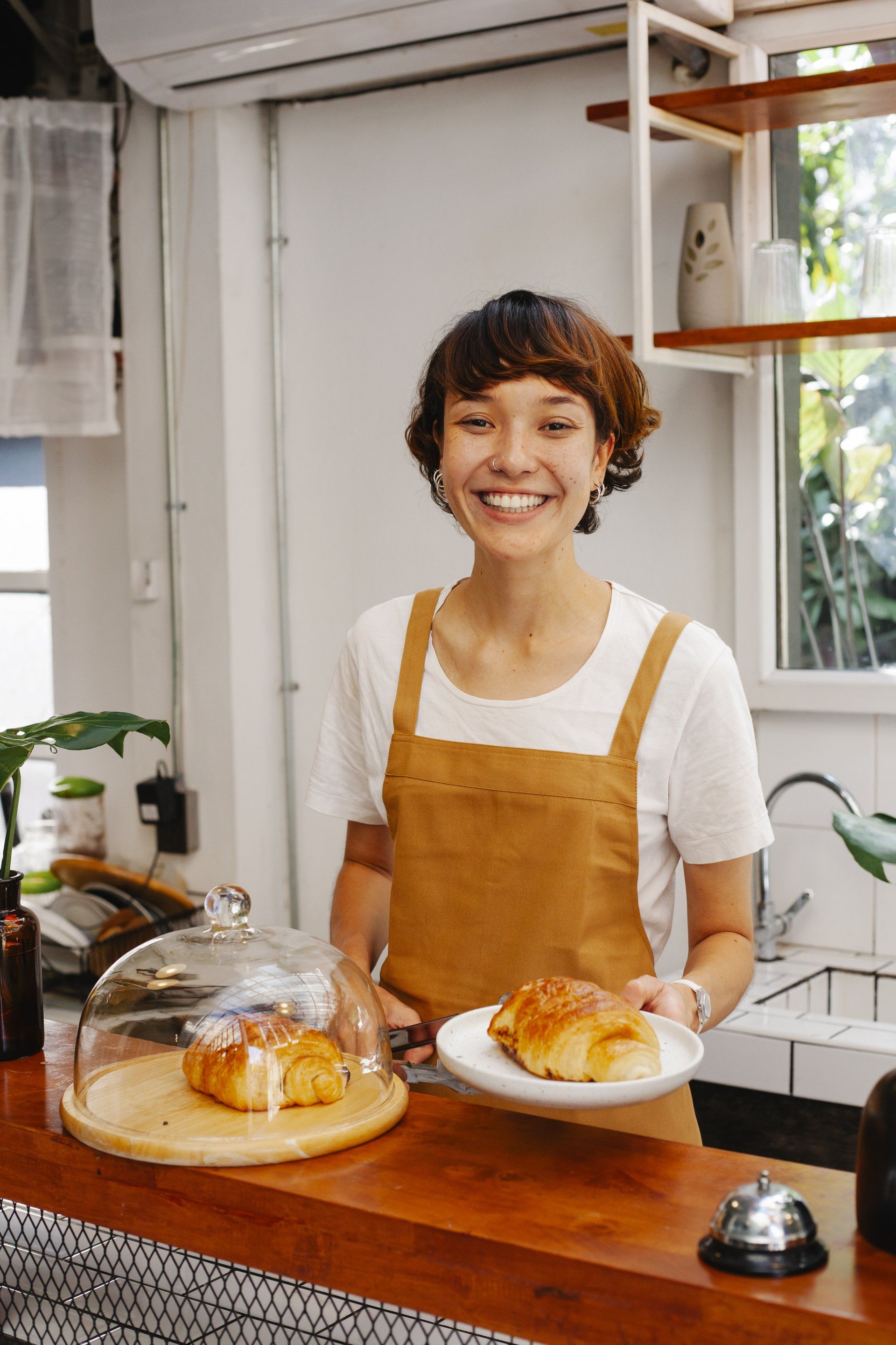 A woman is standing behind a counter holding a plate of food.