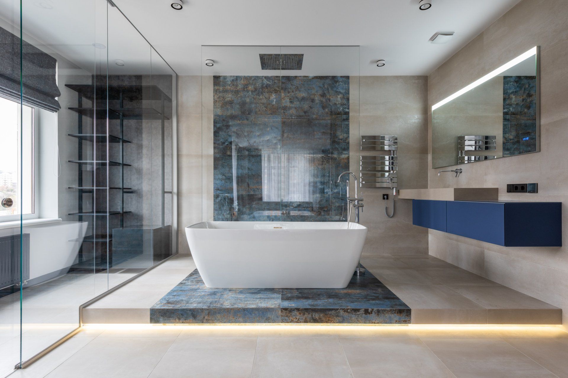 Modern bathroom with a freestanding tub, glass shower, marble walls, and floating blue vanity