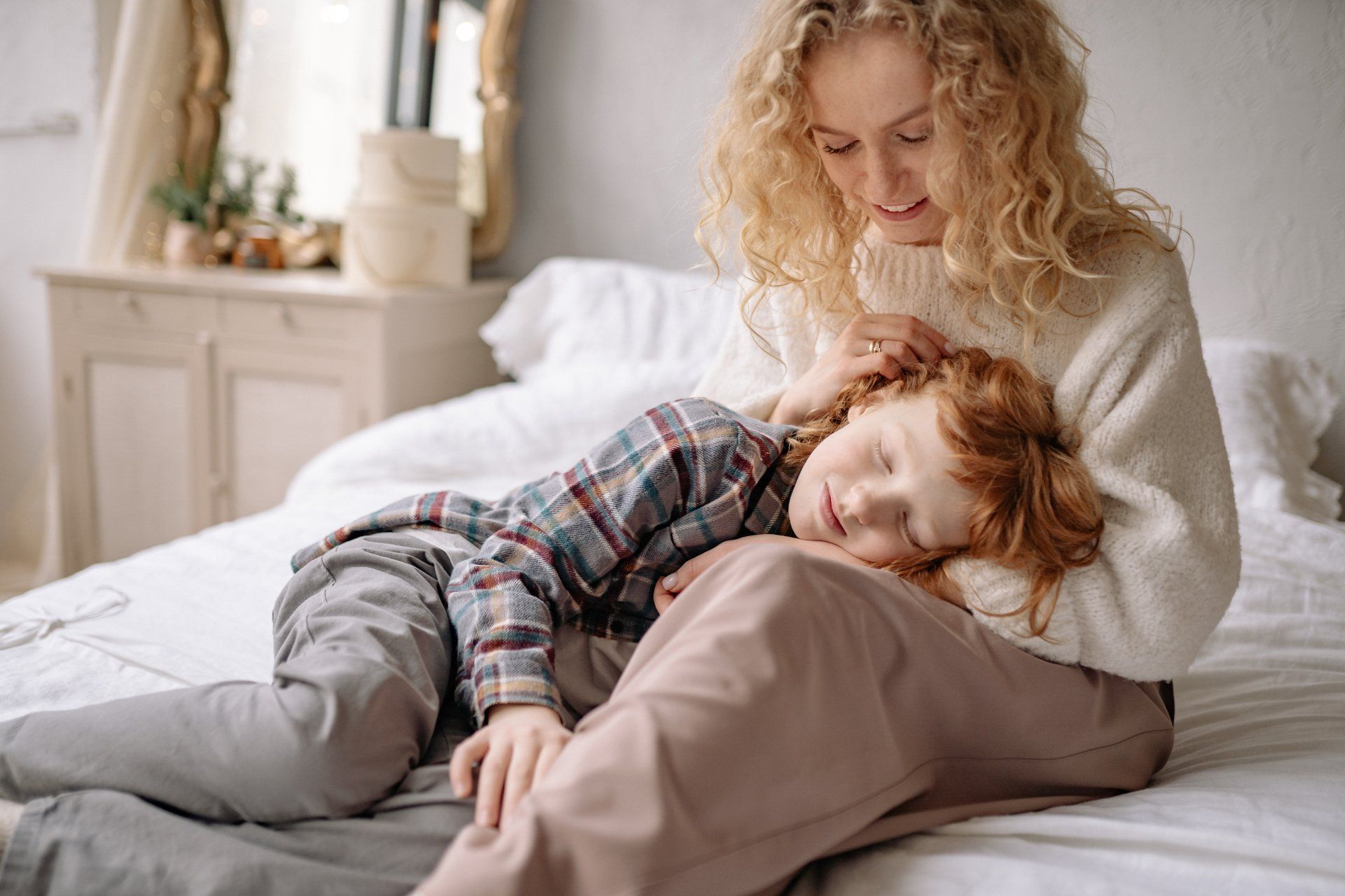A woman is sitting on a bed with a child.
