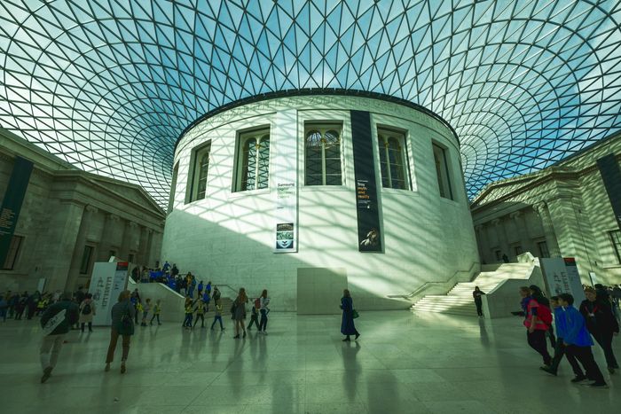 A group of people are standing in front of a large building with a glass ceiling.