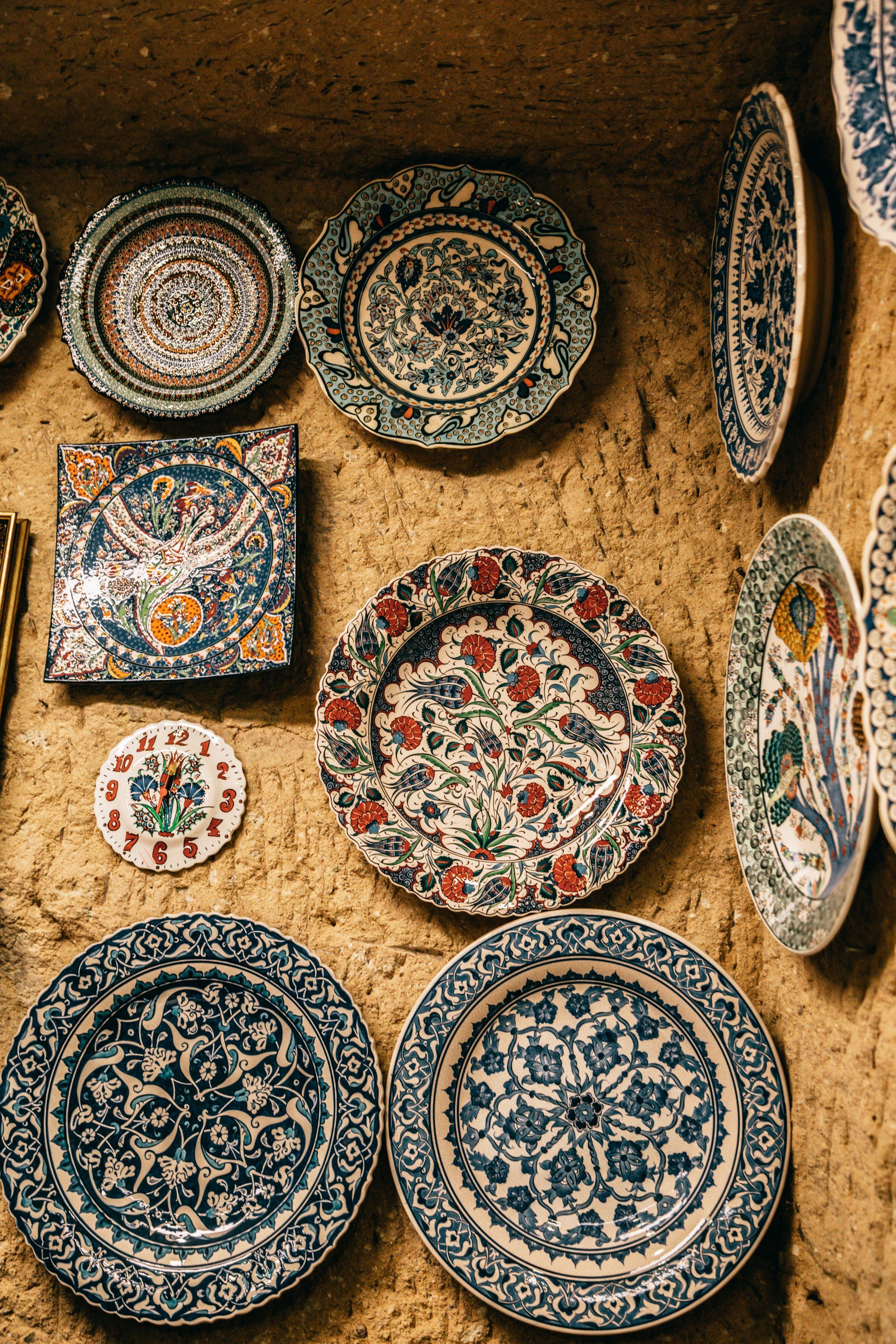 Ceramic plates with floral and geometric patterns, blue and red on beige wall.
