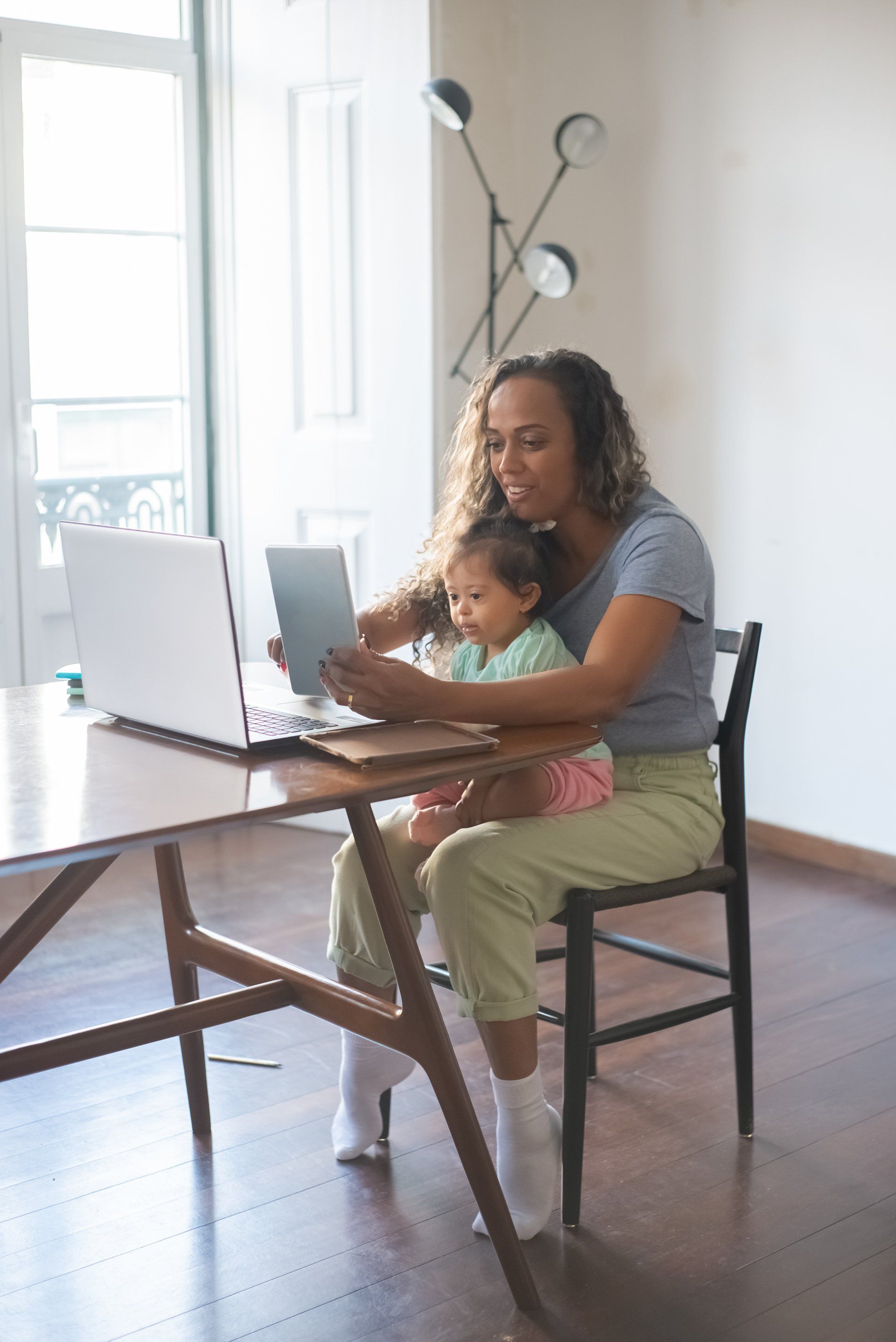 photo of a woman sitting at her work desk with an infant in her lap