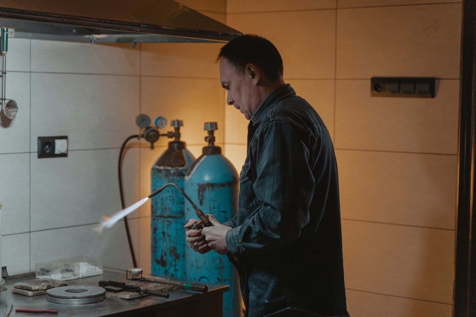 A man is welding a piece of metal in a workshop.