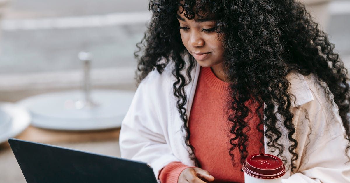 A woman with curly hair is sitting at a table using a laptop computer.