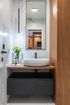 A bathroom with a sink , mirror and wooden cabinet.
