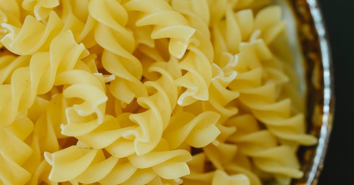 Close-up of uncooked rotini pasta in a metal bowl