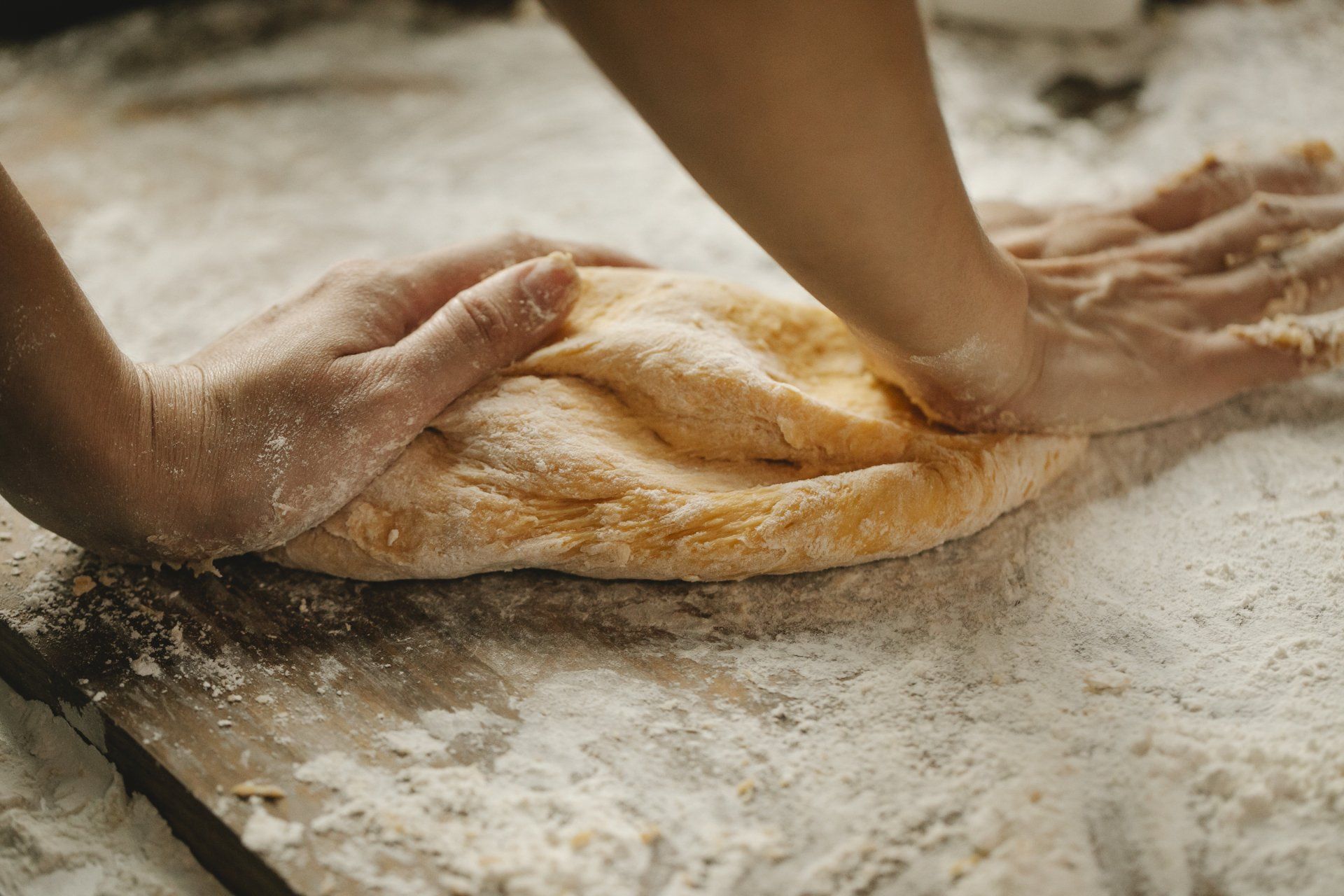 A person is kneading dough on a table covered in flour.