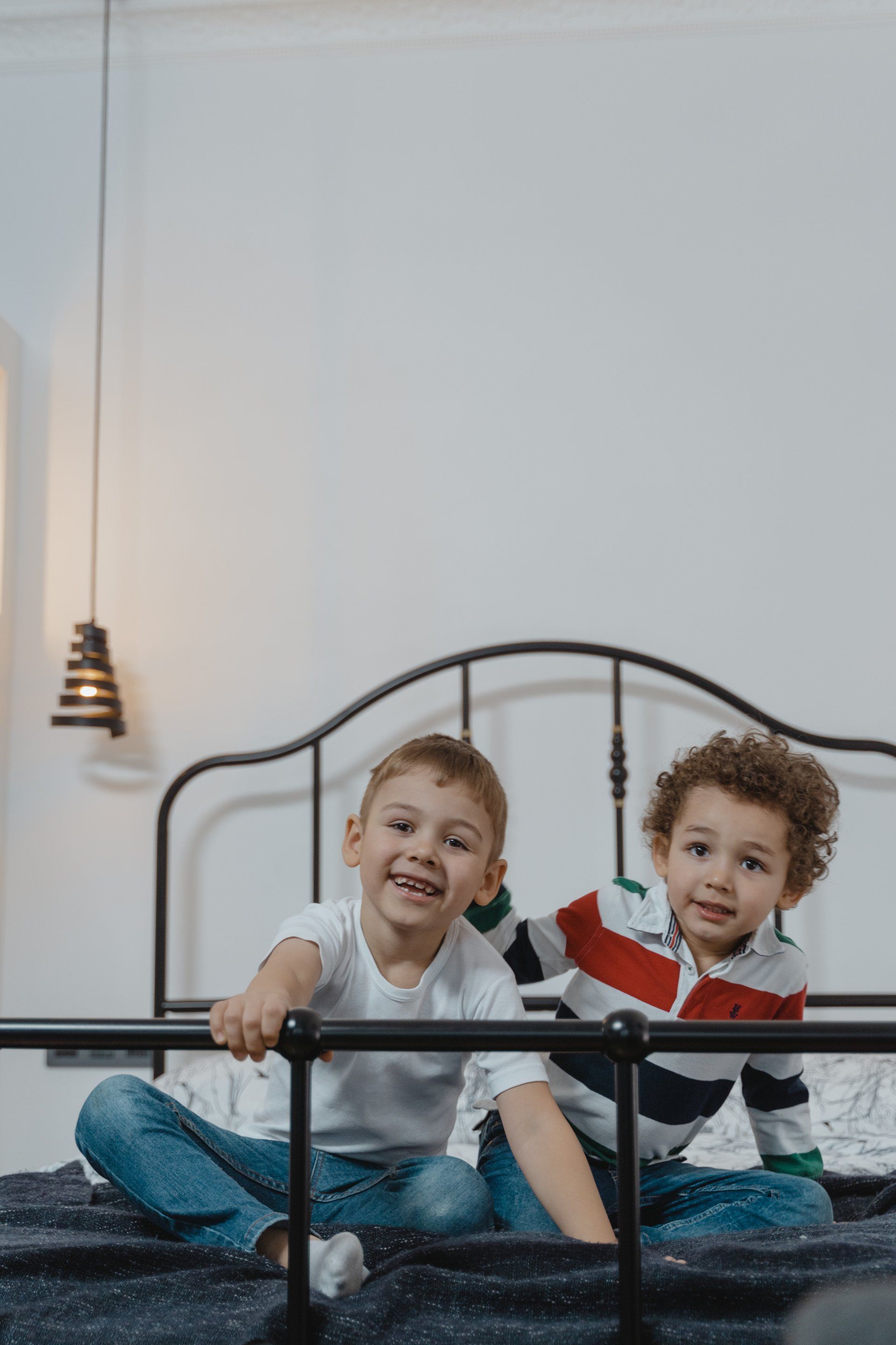 Two young boys are sitting on a bed.