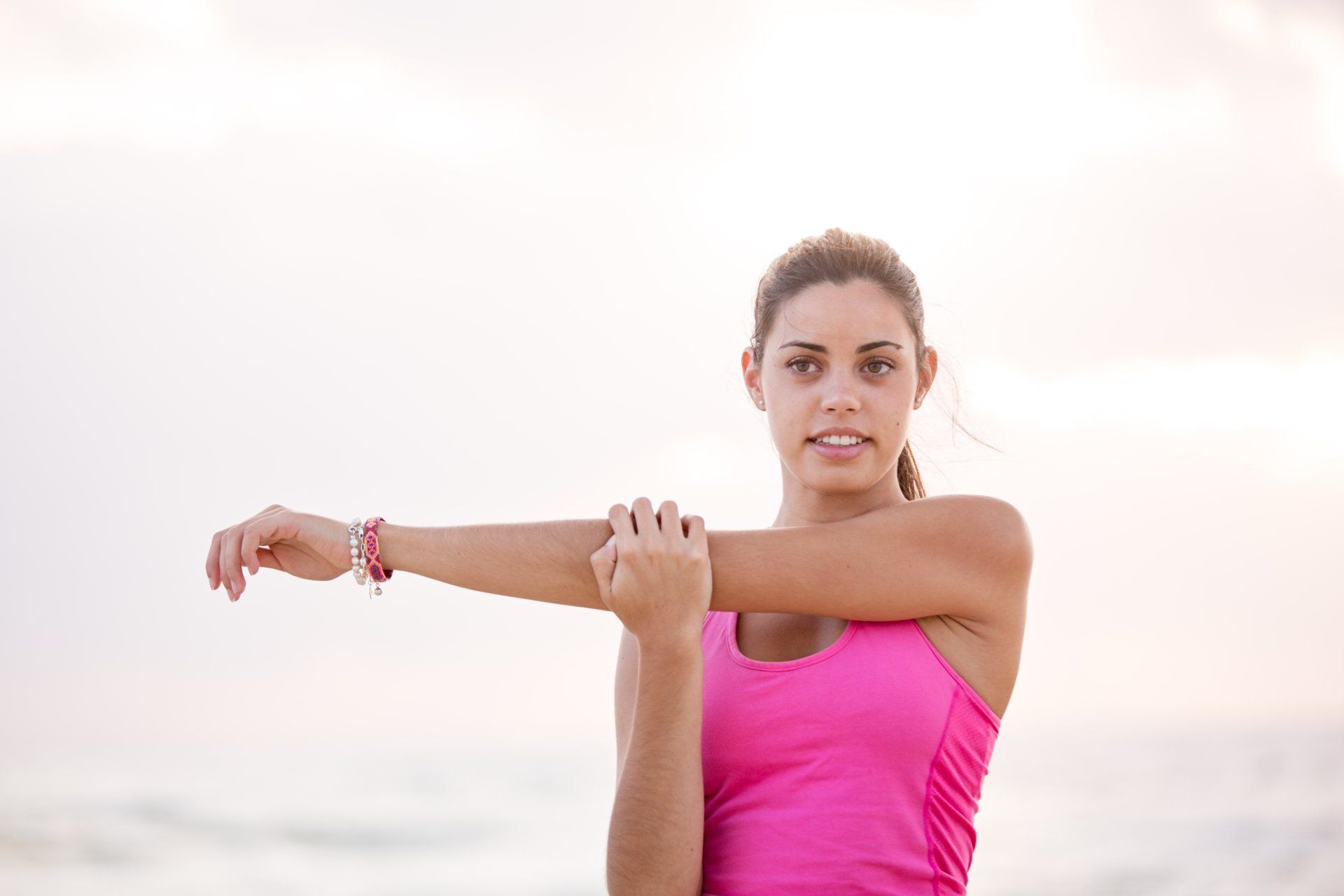 A woman is stretching her arms on the beach.