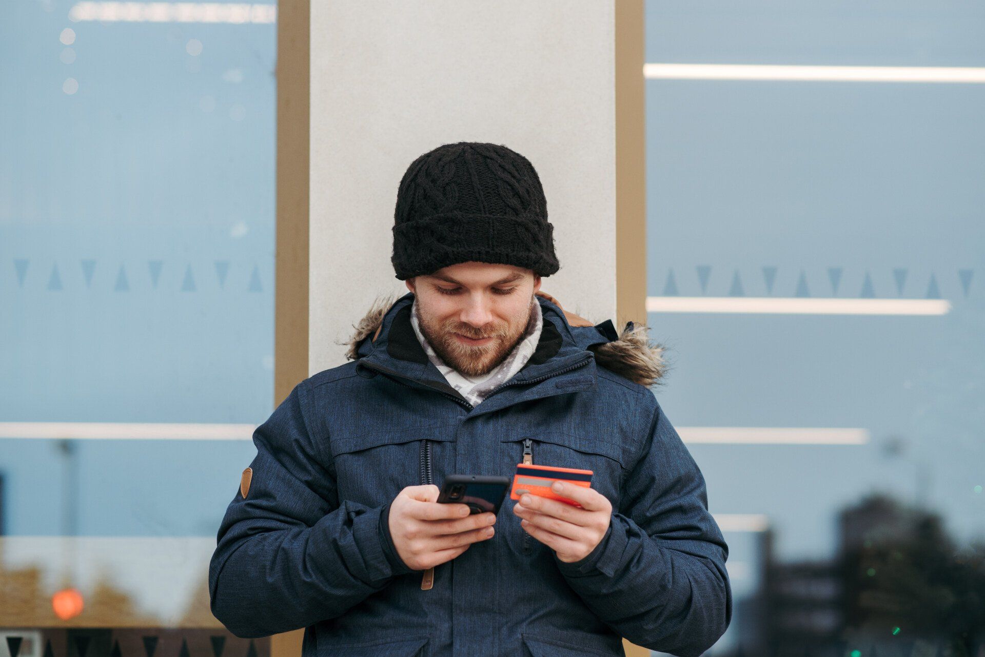 A man is holding a credit card and a cell phone.