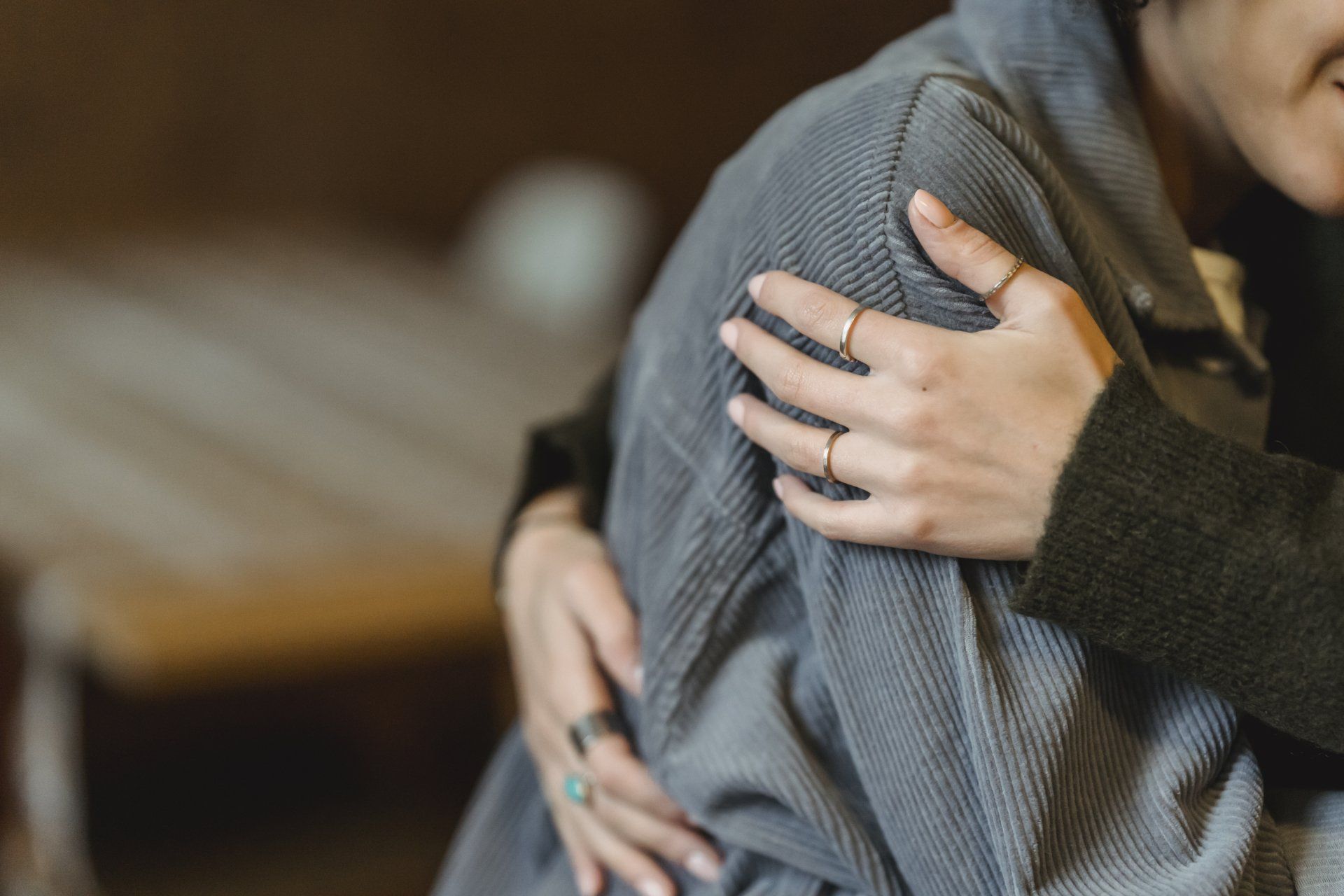 A woman is hugging a person in a grey sweater.