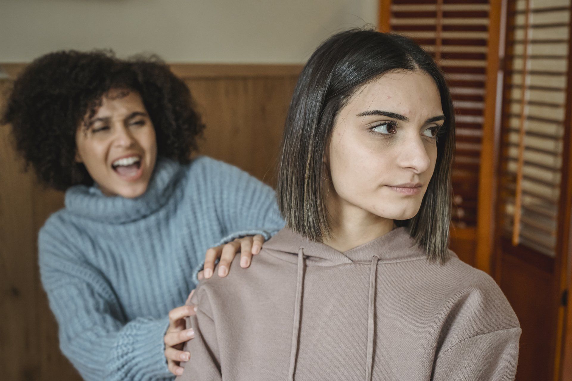 A woman is putting her hand on another woman 's shoulder.