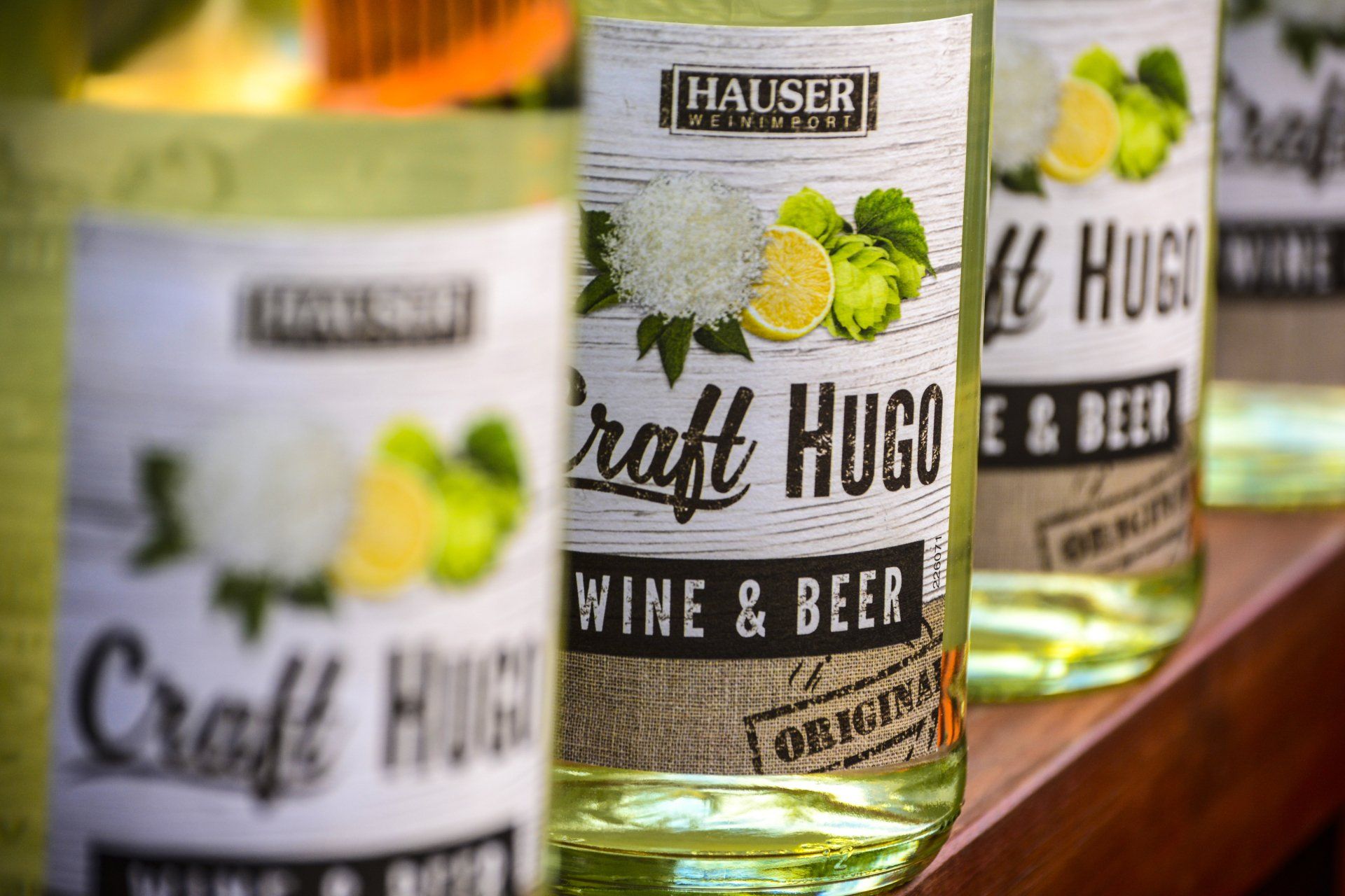 Bottles of Hauser Craft Hugo Wine & Beer, labels with fruit and hops.