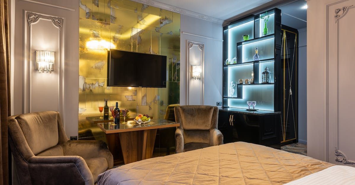 A hotel room with a bed , chairs , table and television.