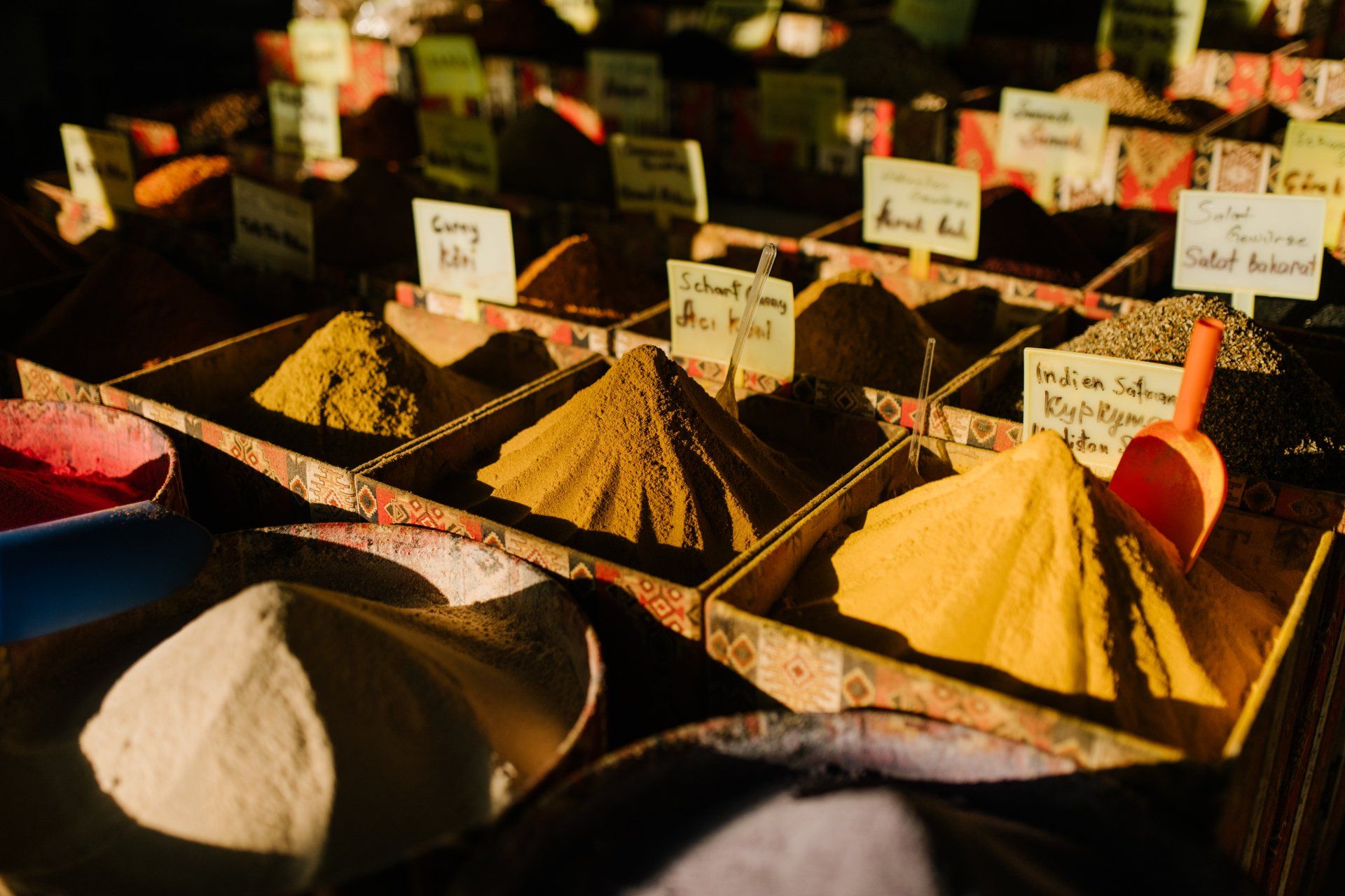 A variety of spices are displayed in boxes on a table.