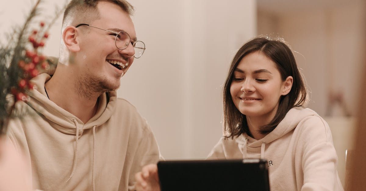 un uomo e una donna guardano un tablet e sorridono