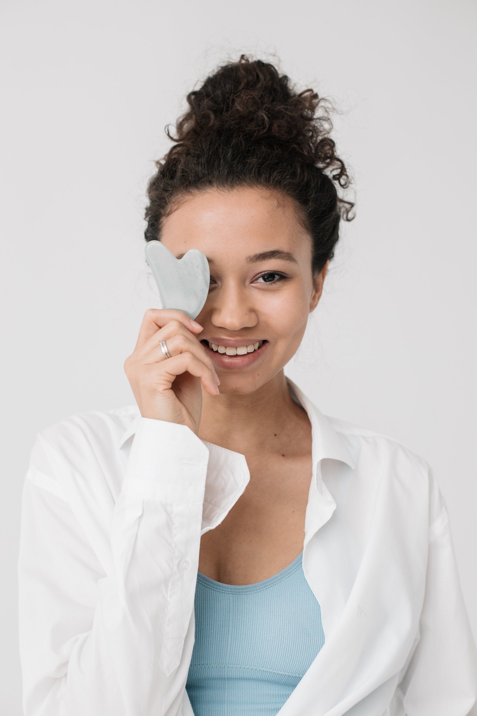 A woman is holding a heart in front of her eye.