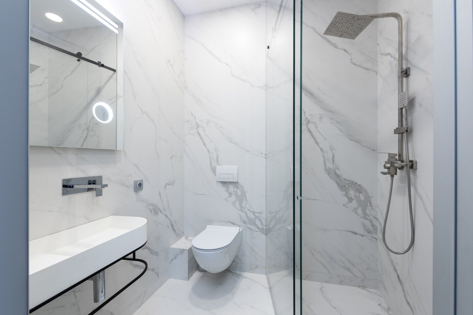 A bathroom with a toilet , sink , shower and mirror.