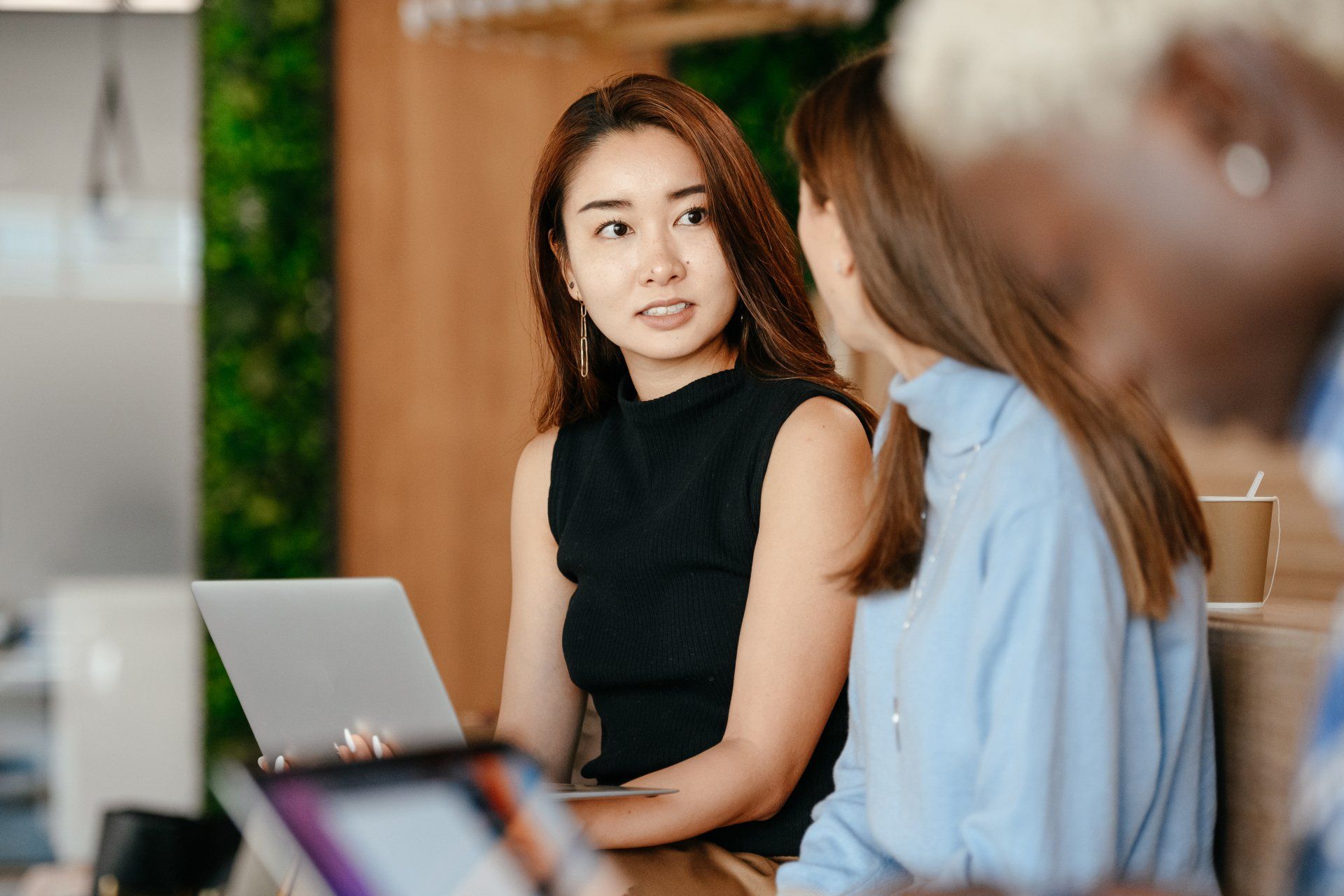 A group of women are sitting at a table with laptops.