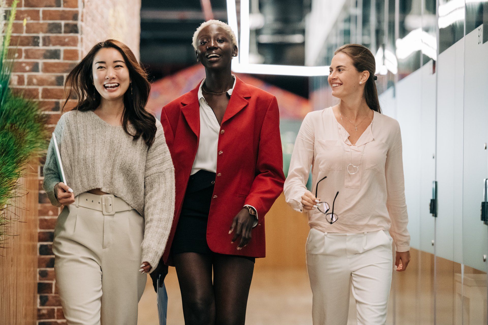 Three women are walking down a hallway together to Unlock your team's potential with customized training solutions designed to boost productivity, enhance skills, and drive business success