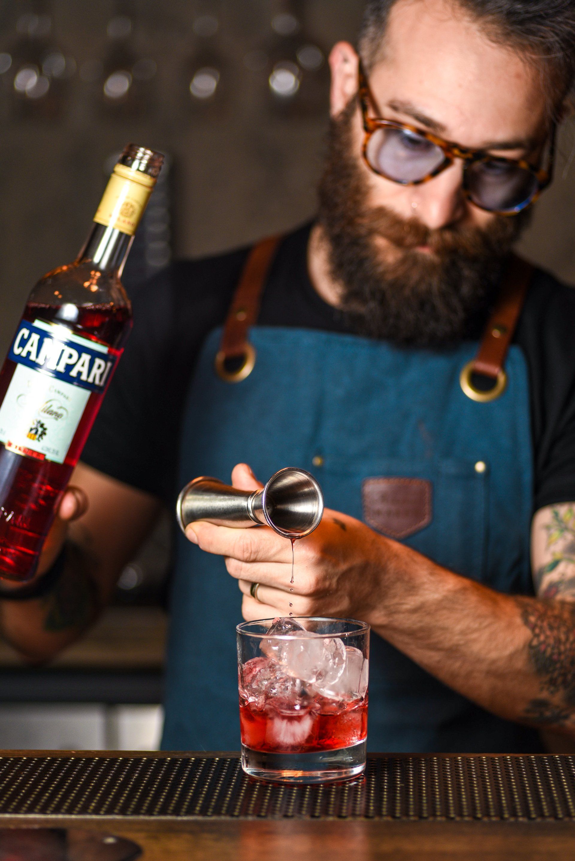 Un barista versa del Campari in un bicchiere con ghiaccio.