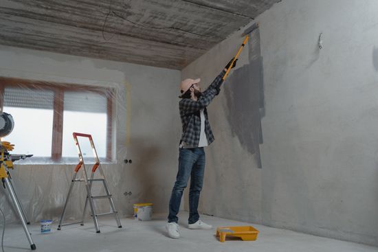 a man is painting a wall with a paint roller