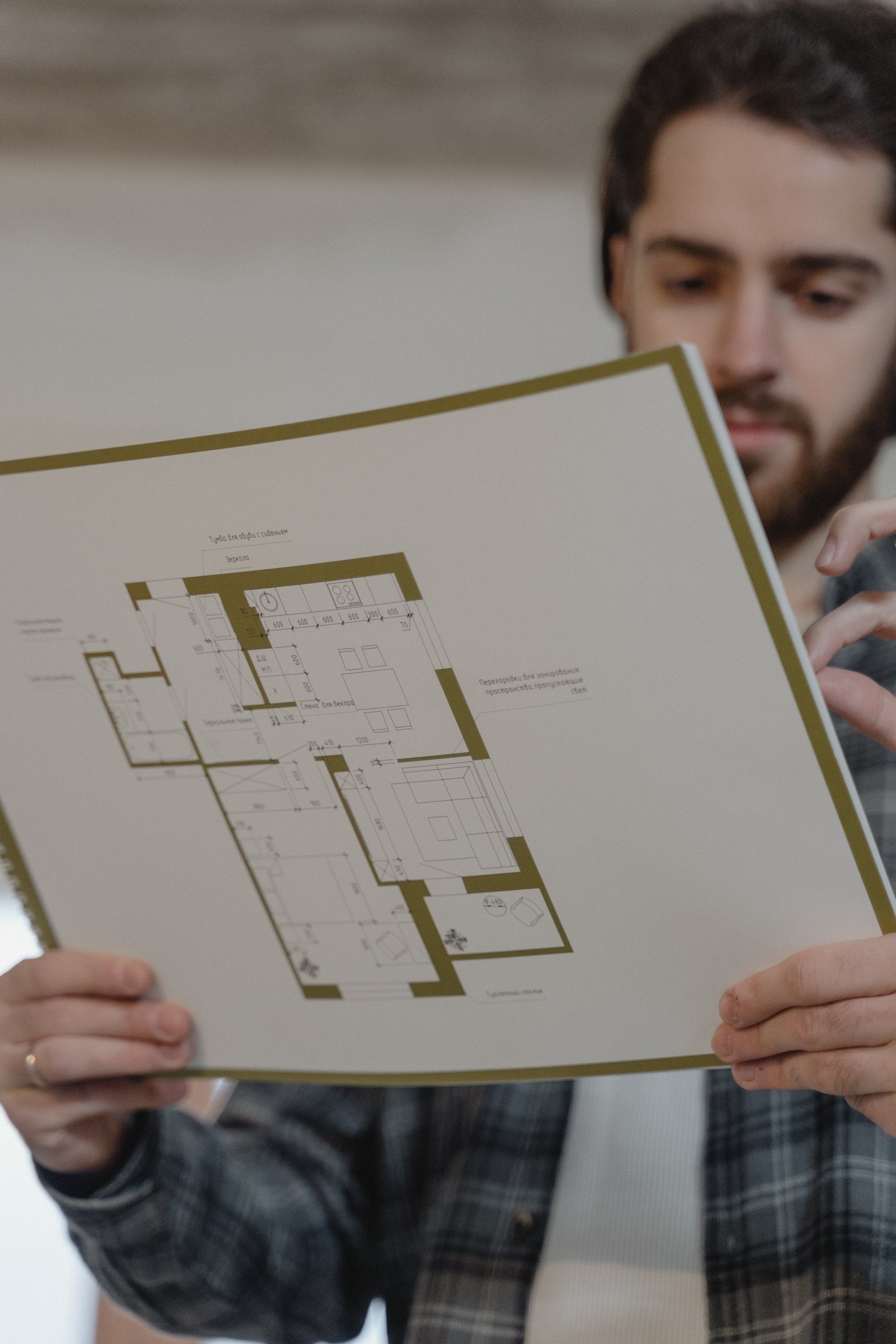 A man is holding a piece of paper with a floor plan on it