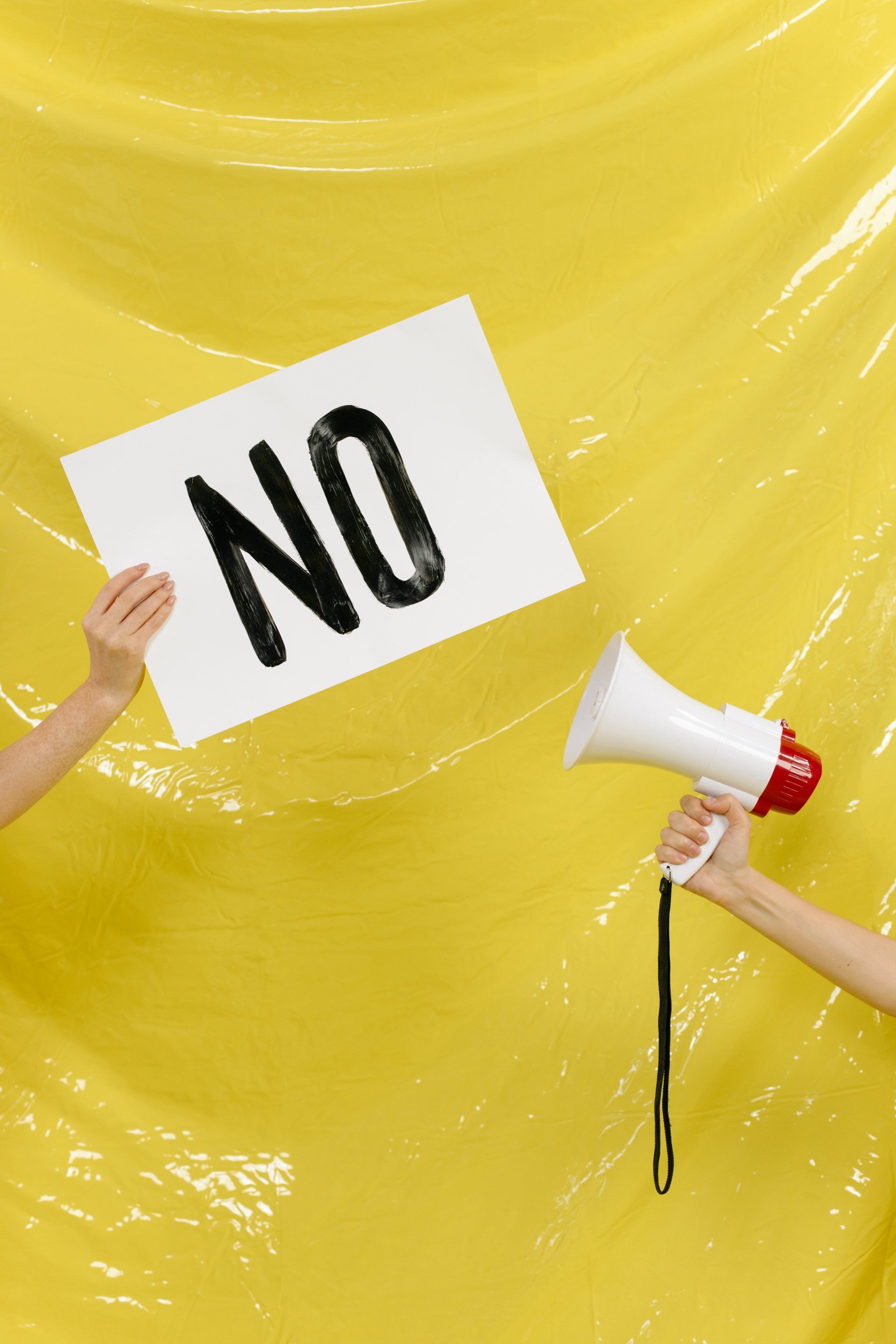 A person is holding a megaphone and a sign that says no.