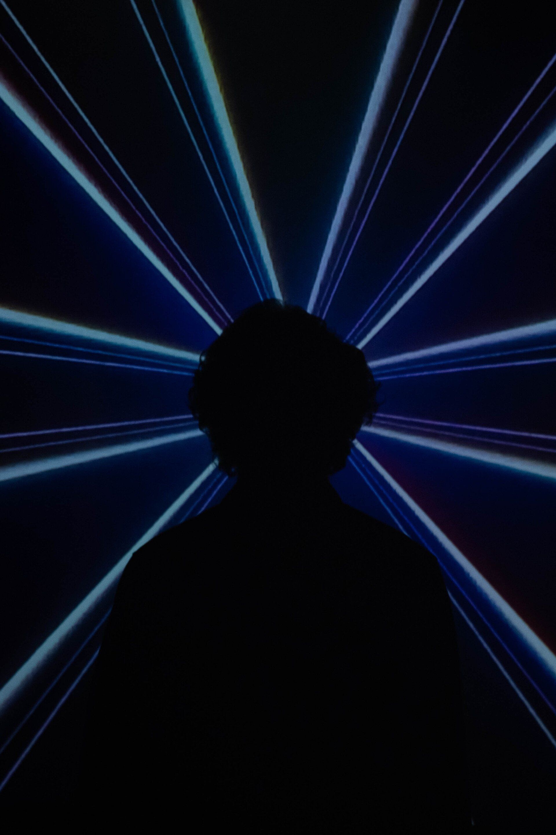 A silhouette of a person in a dark room with blue lights coming out of it.