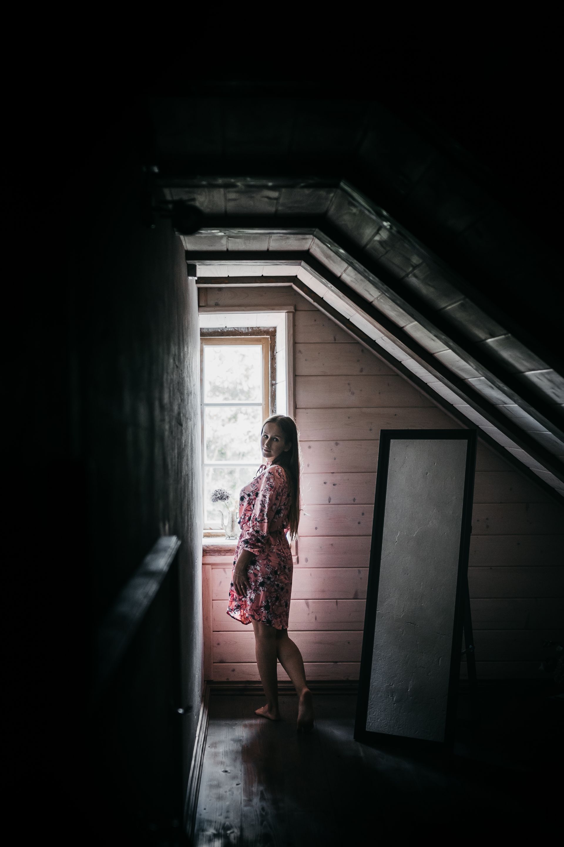 a woman standing by the attic's window