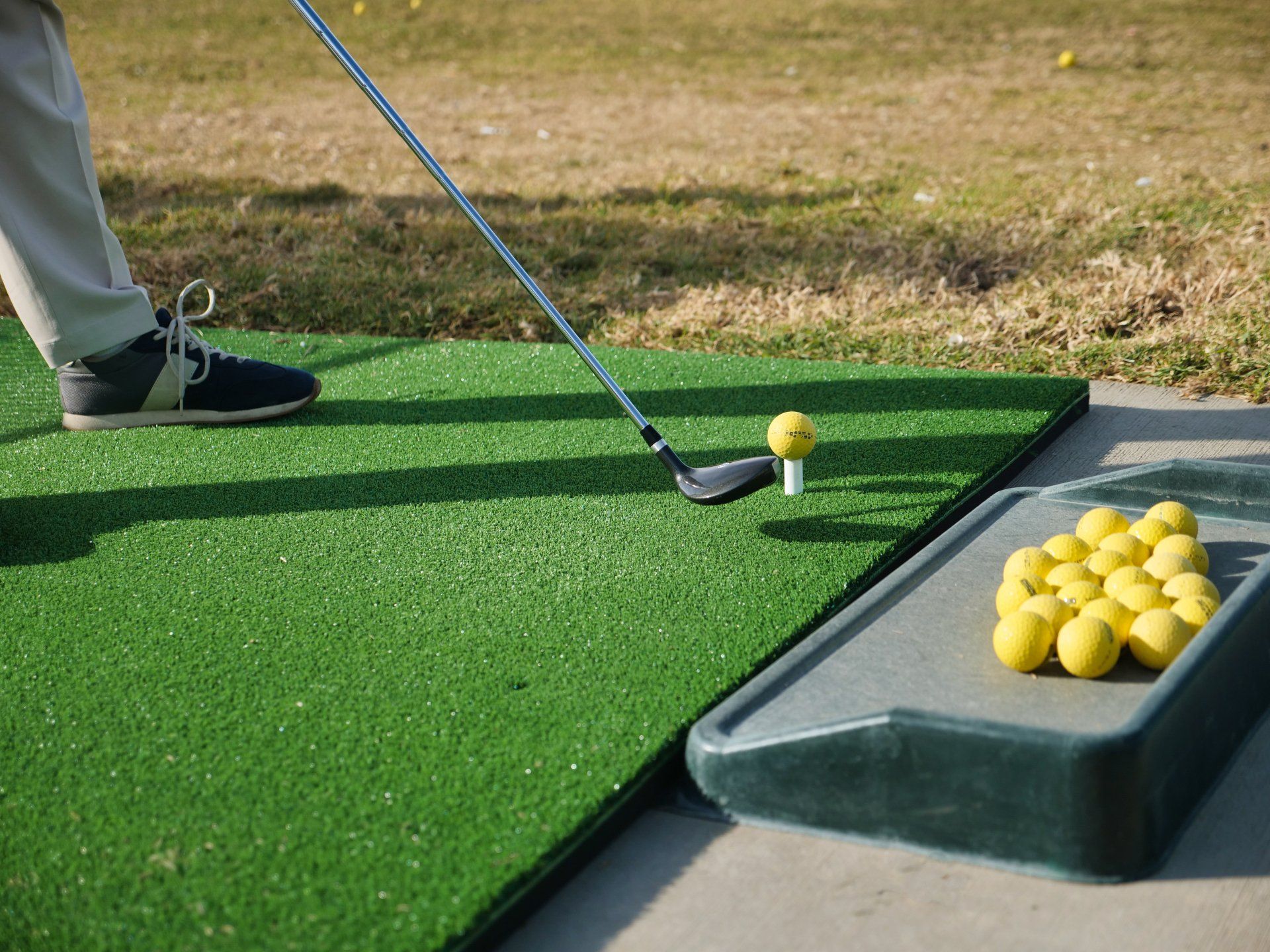 A person is swinging a golf club at a golf ball on a golf course.