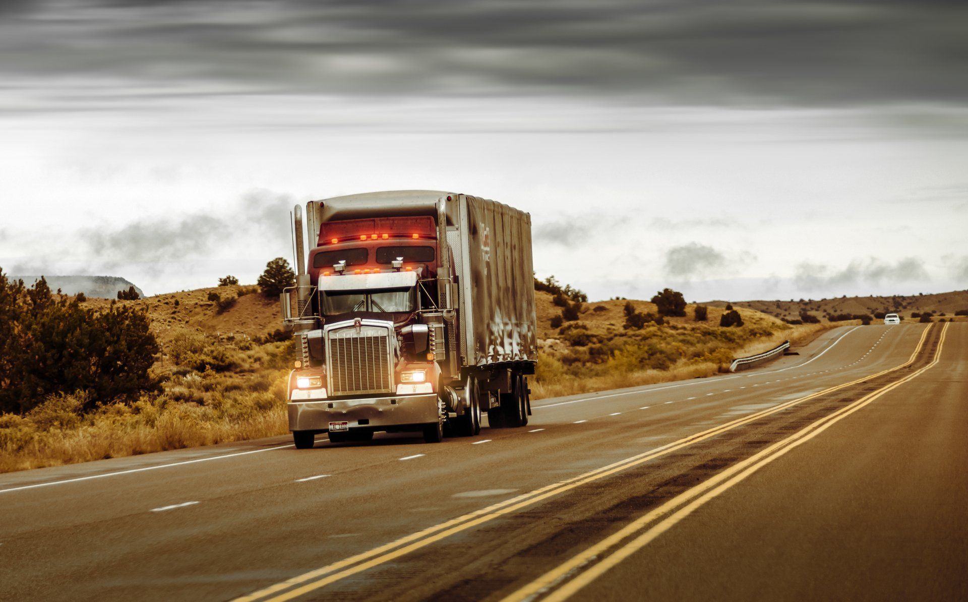 A semi truck is driving down a highway in the desert.