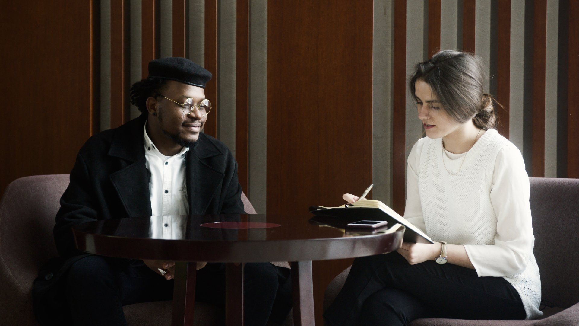 A man and a woman are sitting at a table talking to each other.