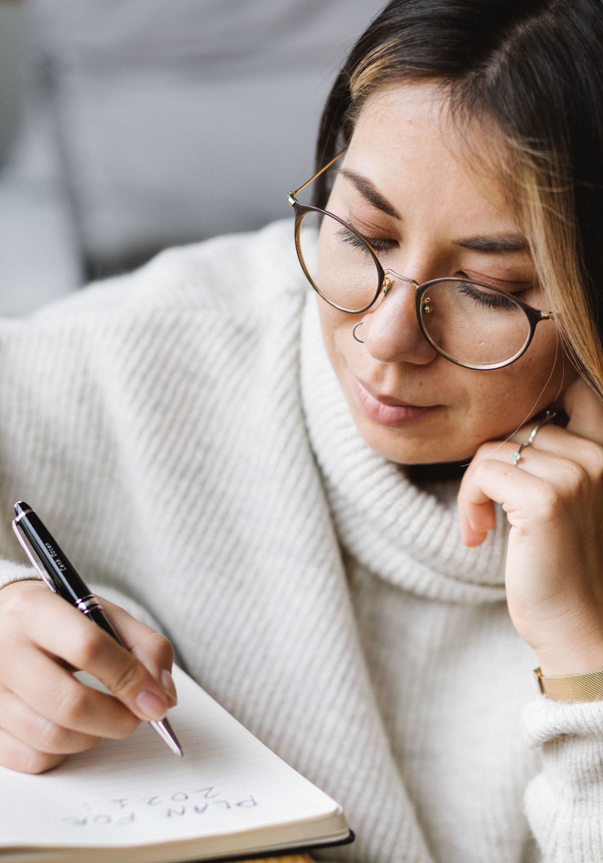 Editorial and Blogs. A woman wearing glasses is writing in a notebook .