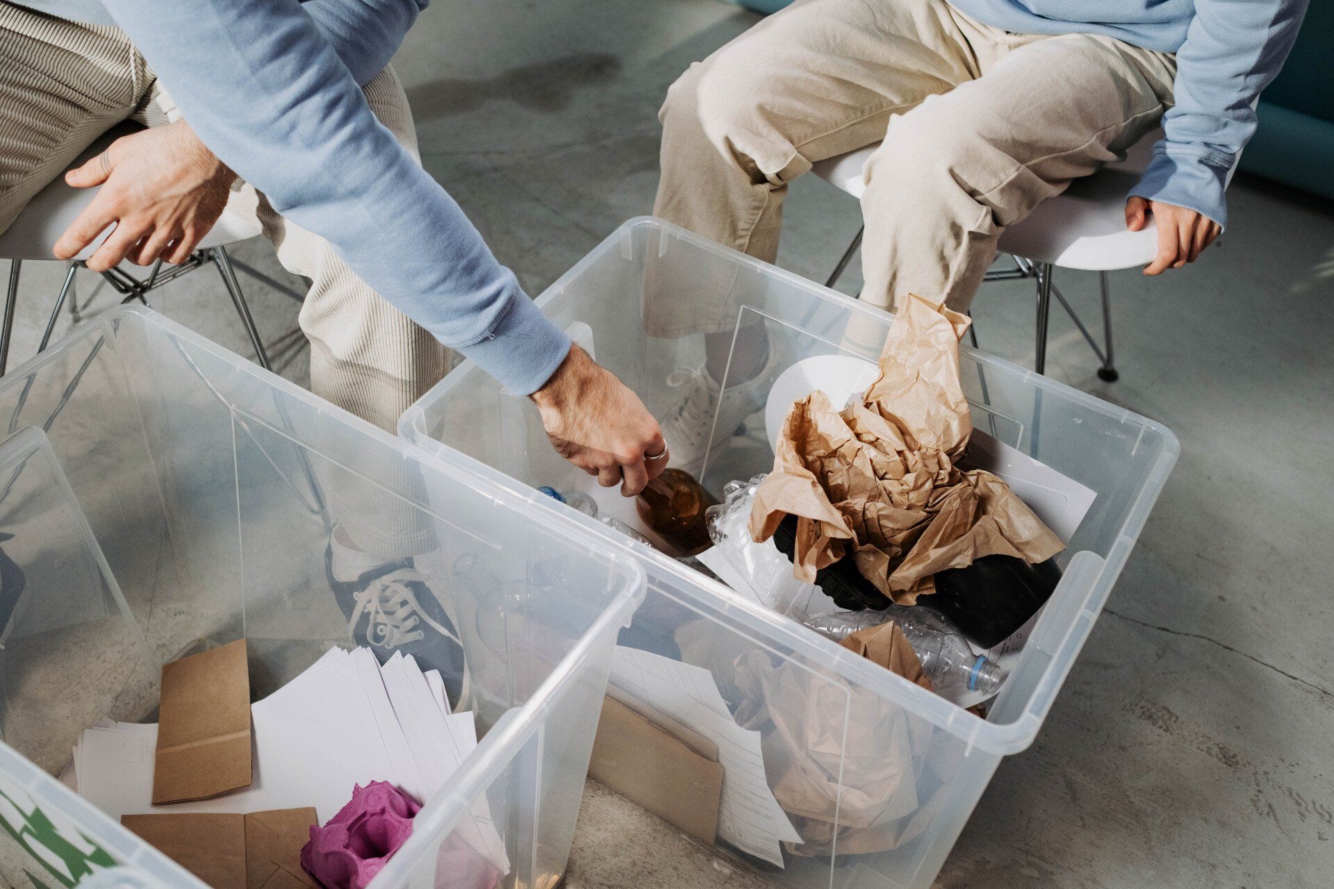 A man is putting something in a clear plastic bin.