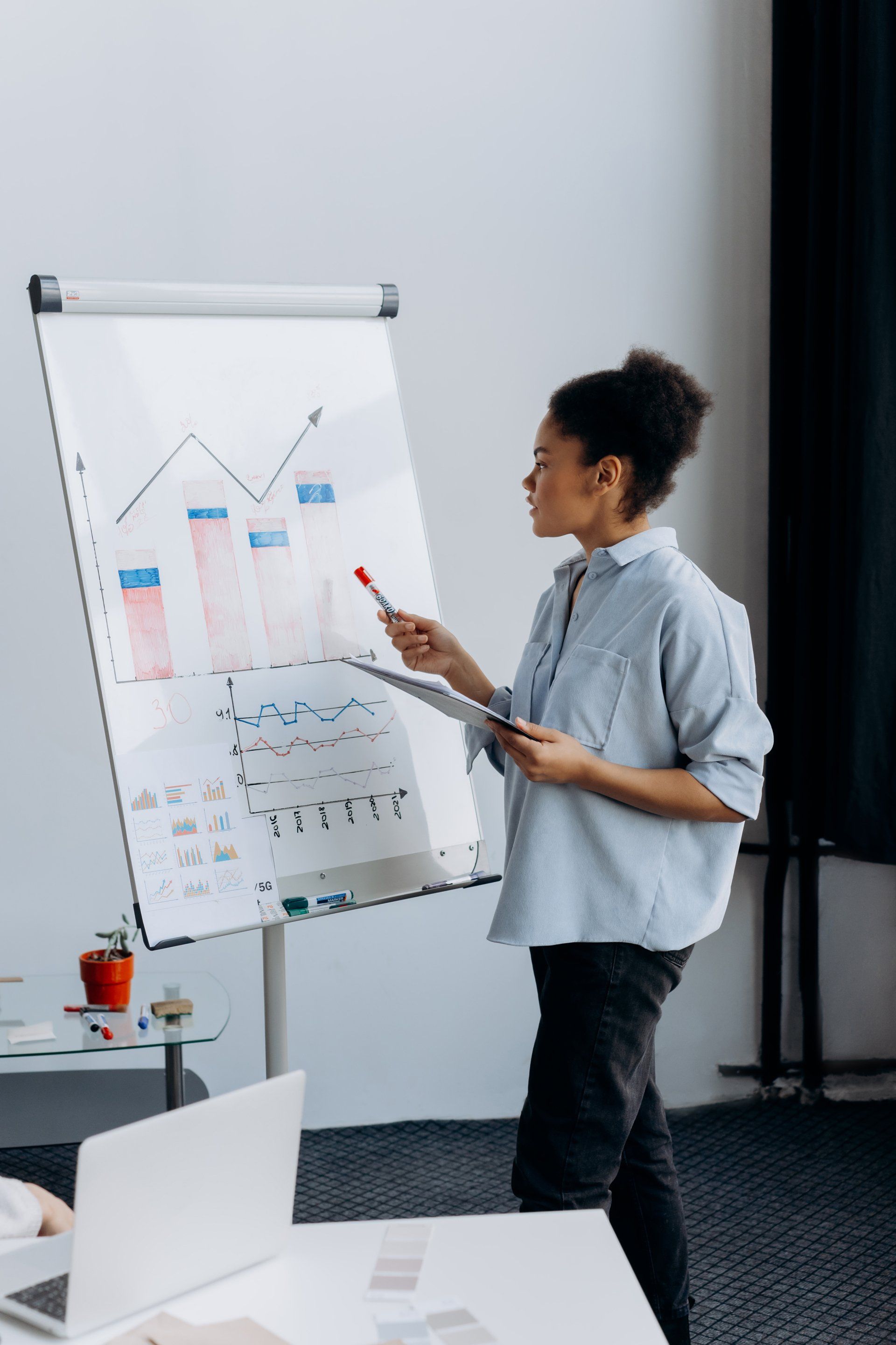 A woman is standing in front of a whiteboard giving a presentation.