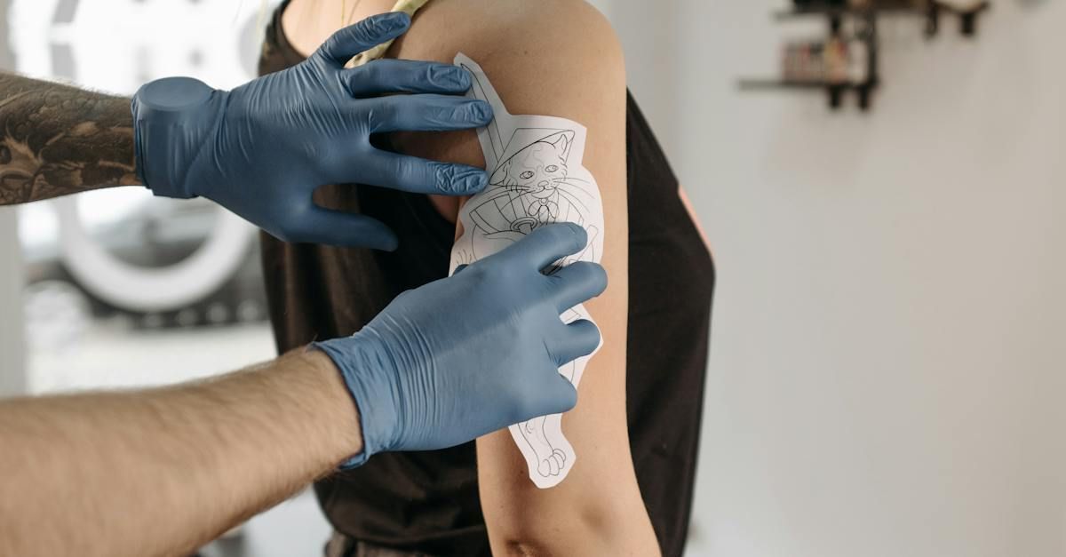 Een tatoeëerder met blauwe handschoenen brengt in een tattooshop een sjabloon aan op de bovenarm van een klant.