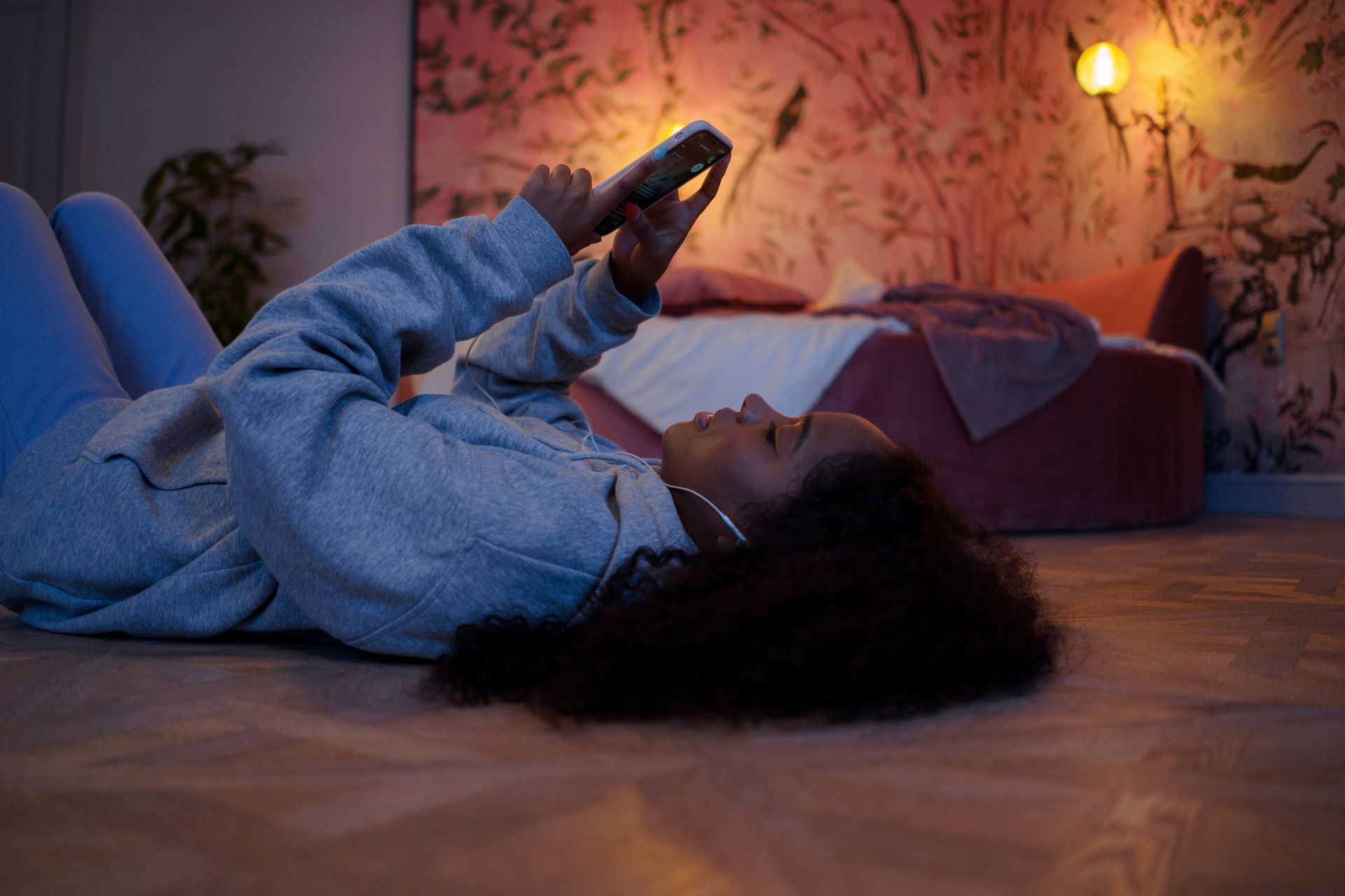 A woman is laying on the floor using a cell phone.