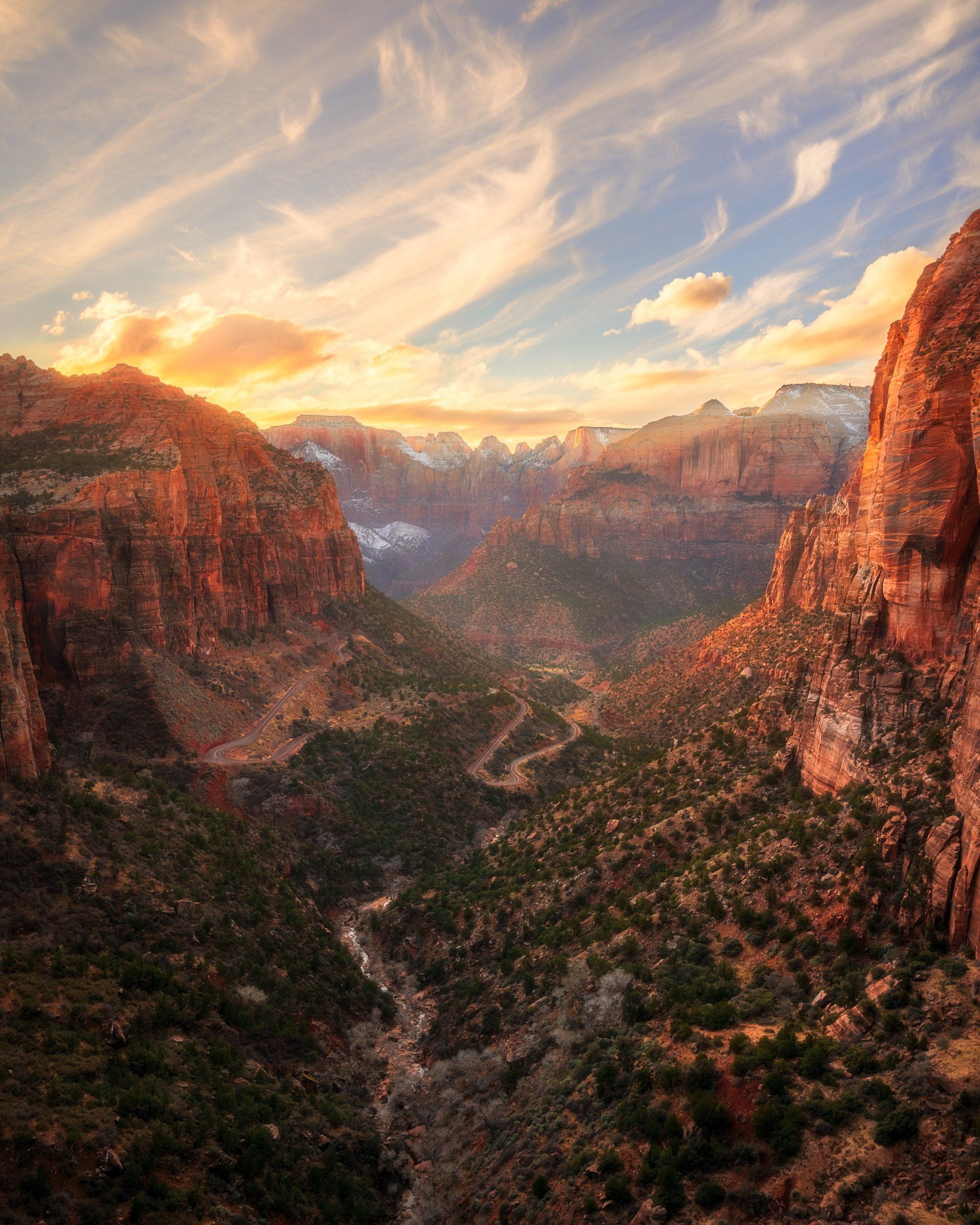 An aerial view of a canyon at sunset with mountains in the background.