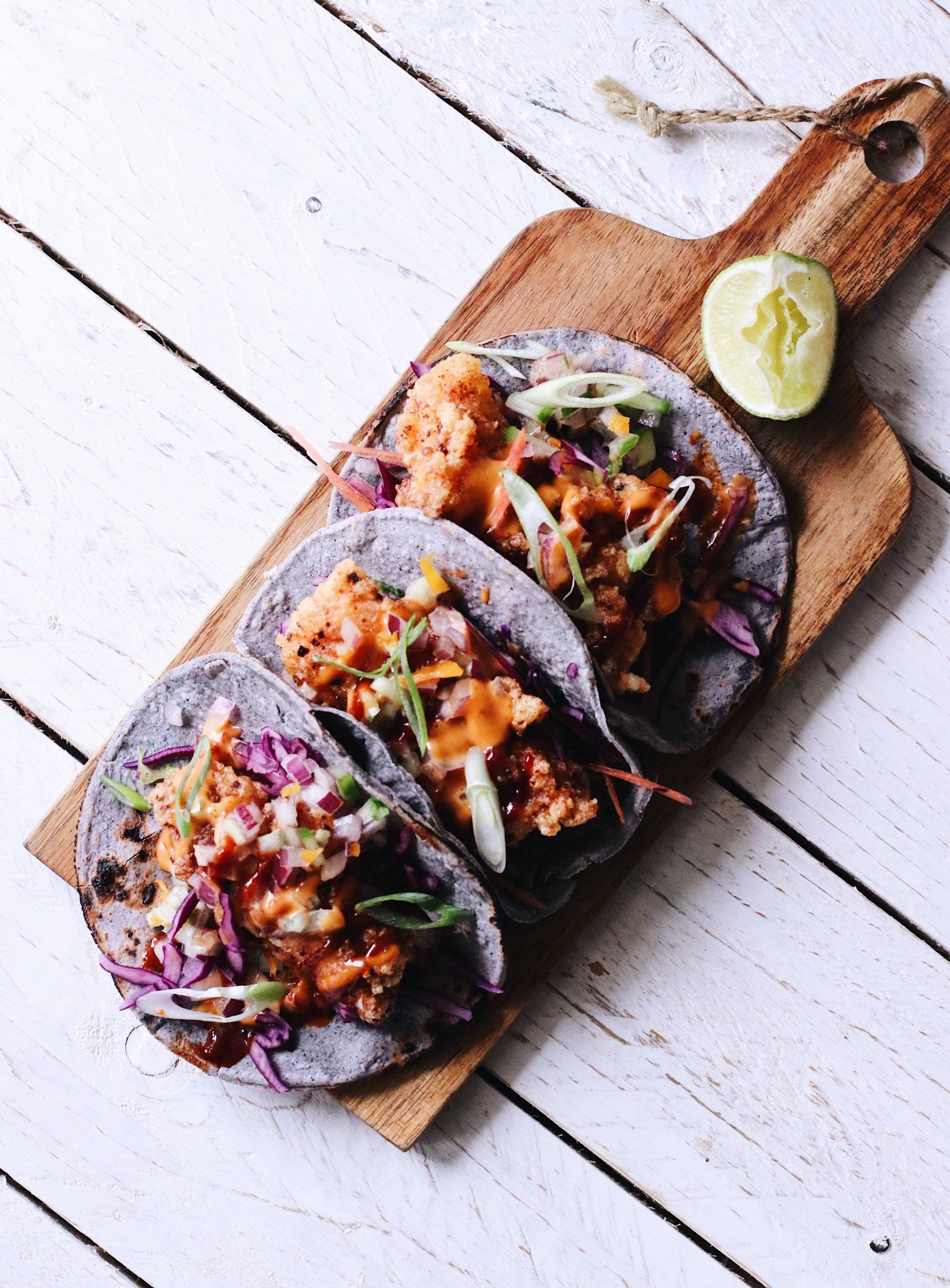 Three crispy Mexican street tacos with fresh lime