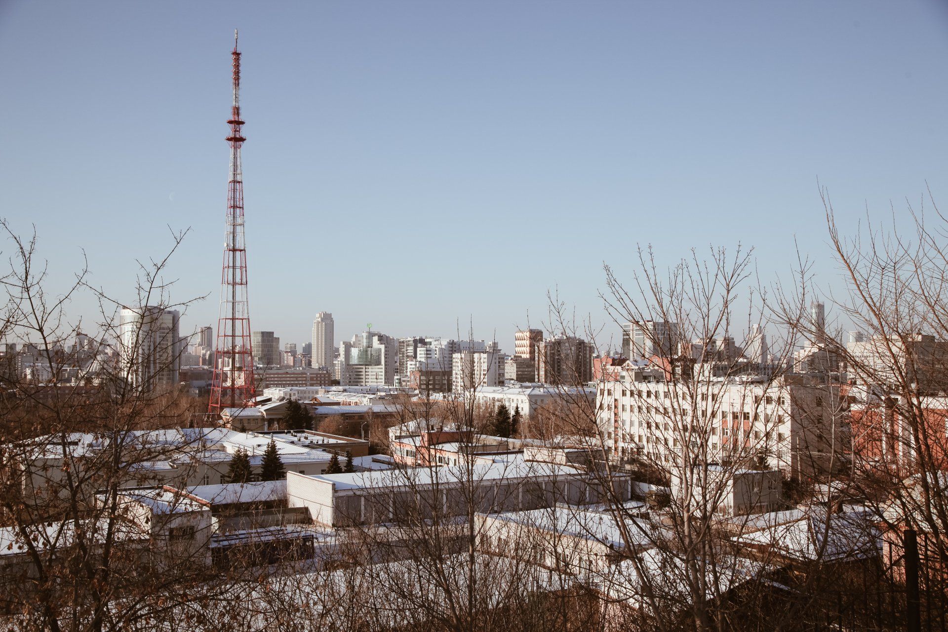 Cityscape with tall communication tower and snowy rooftops under a clear blue sky, Reboot IT’s connected infrastructure.