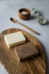 Two bars of soap are sitting on a wooden cutting board.