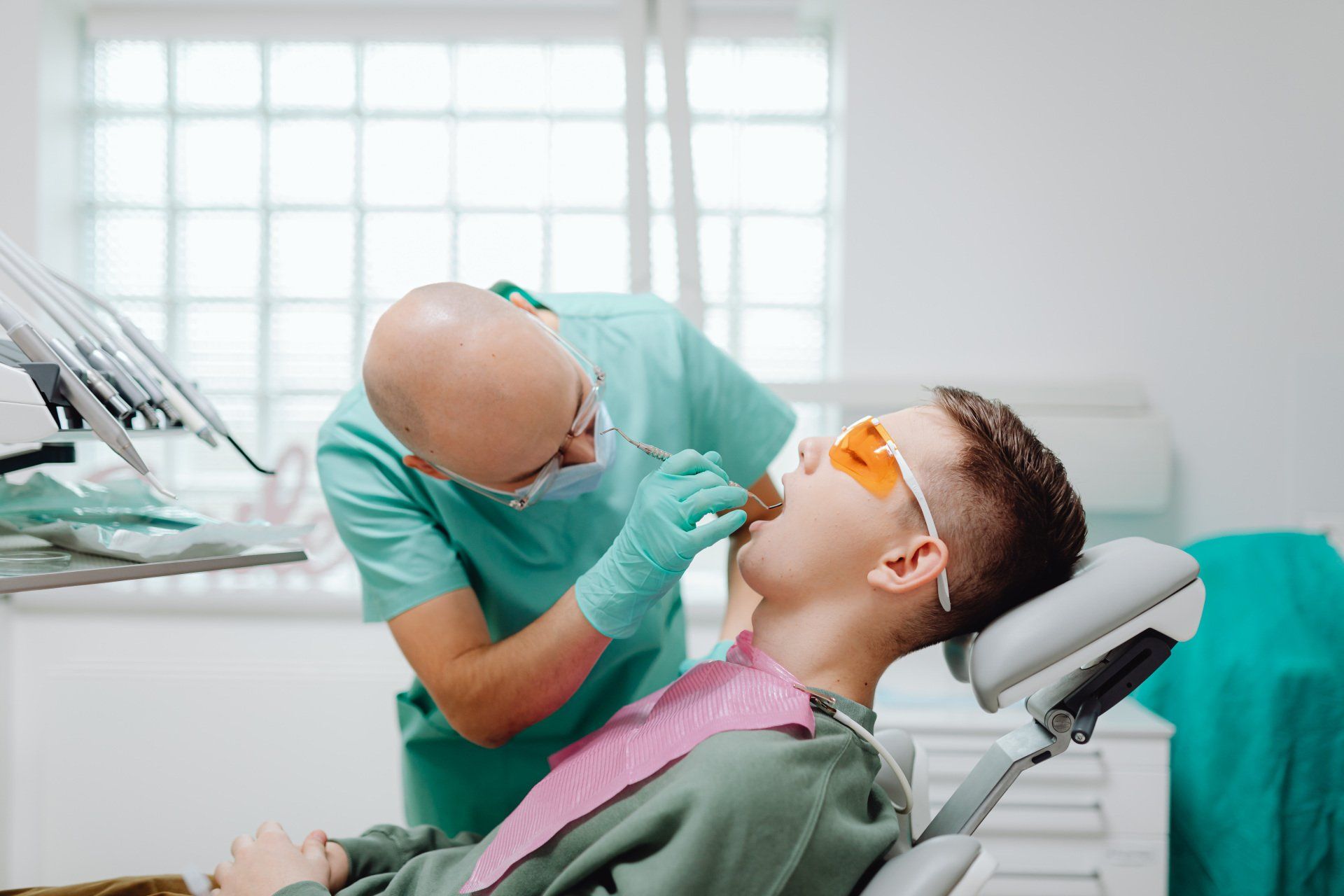 Dentist examining patient's teeth with dental instruments in a clinic setting.